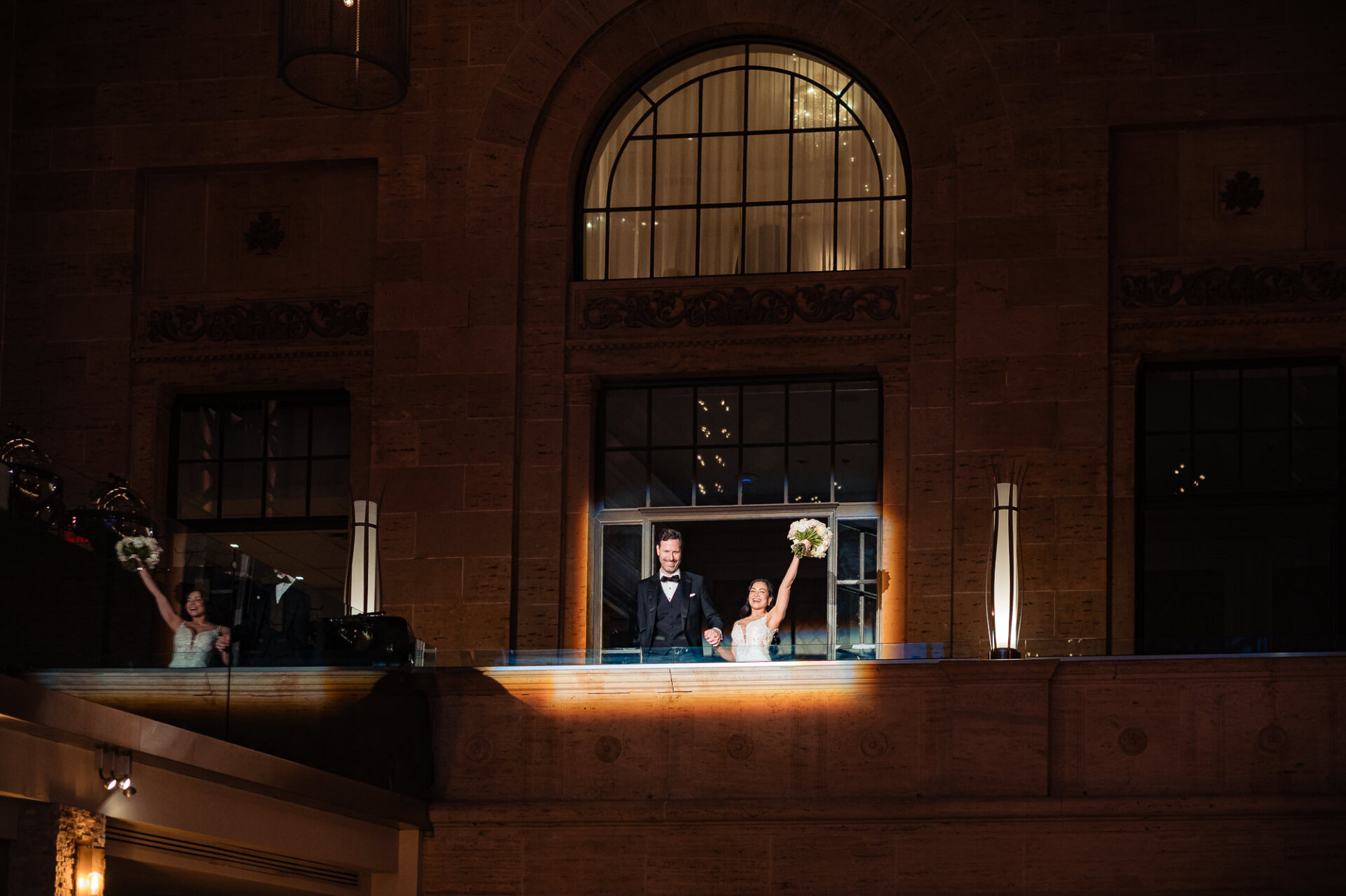 Newlyweds make a celebratory entrance from the balcony overlooking the reception