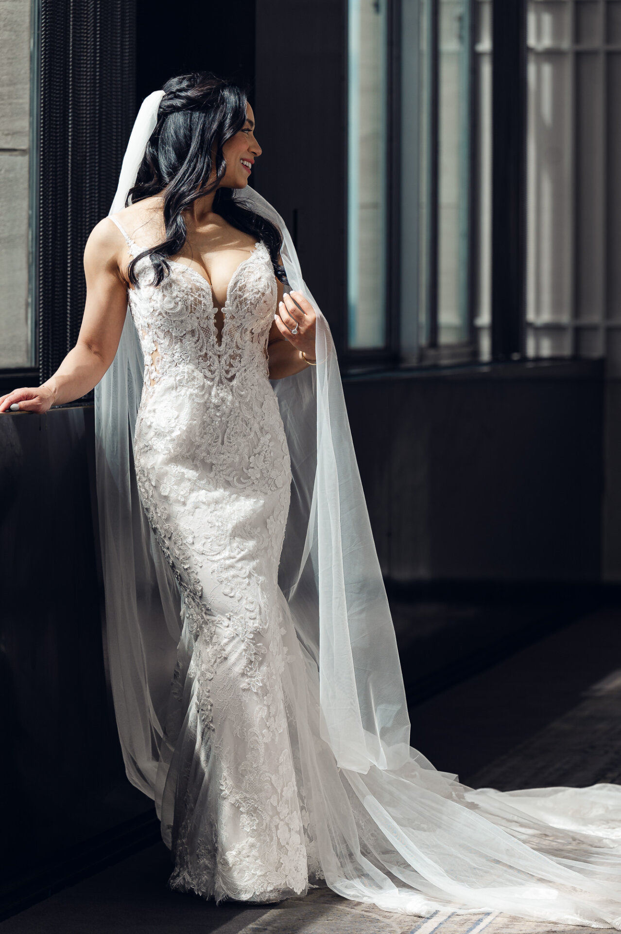 Elegant bridal portrait by the window showcasing intricate lace gown details and natural light