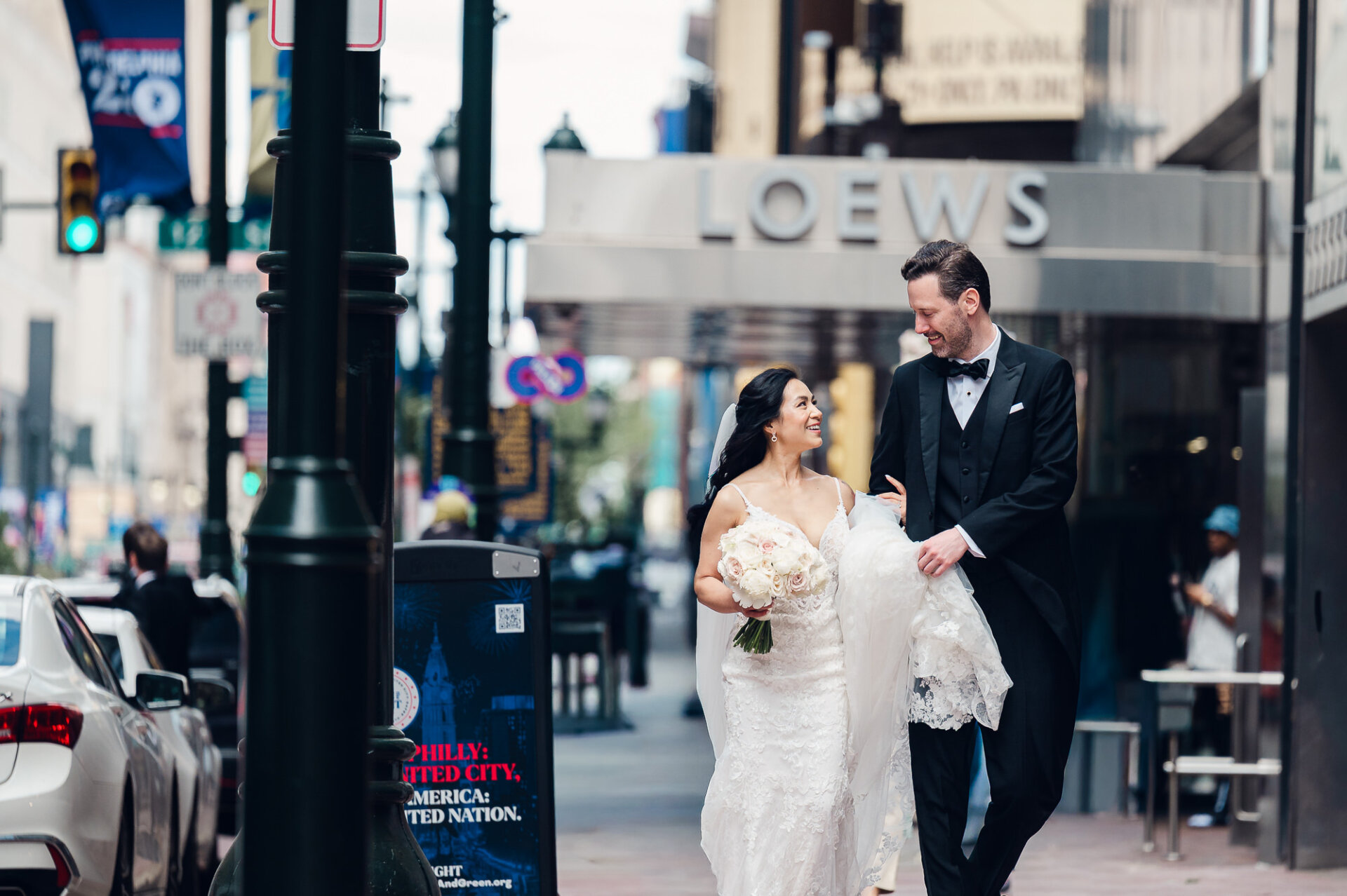 Bride and groom walking through downtown Philadelphia outside the Loews Hotel after their wedding