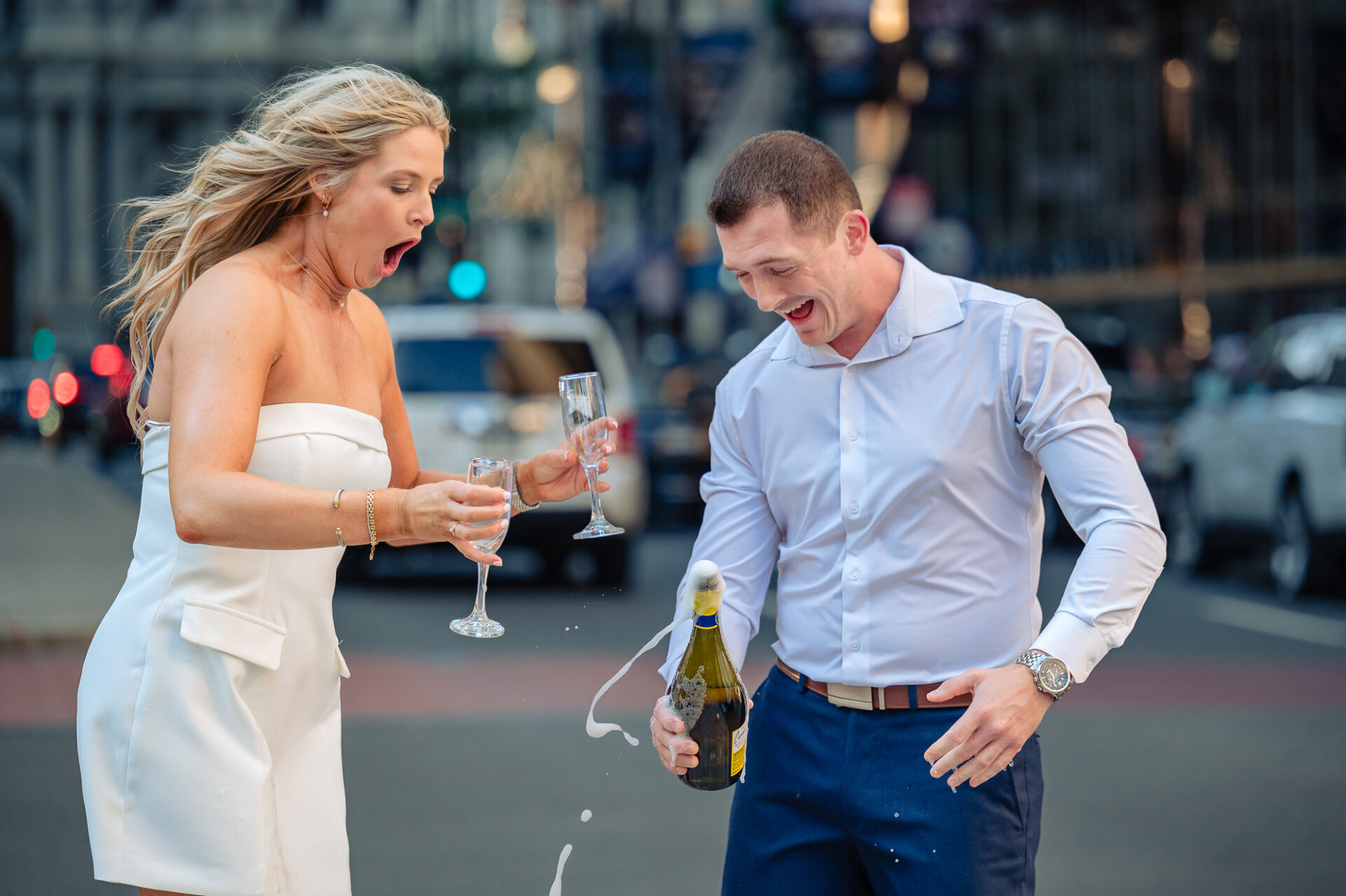 Action shot of champagne spraying everywhere as couple laughs uncontrollably on Broad Street