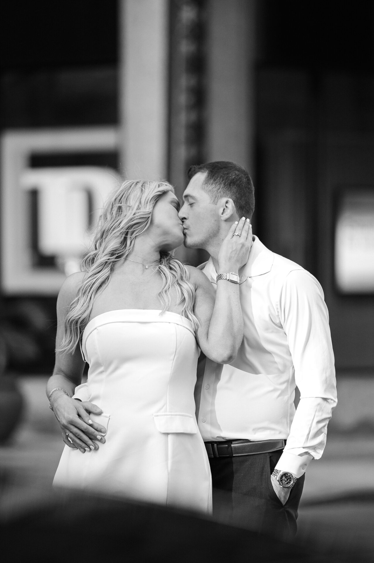 Black and white close-up of bride with hand on groom's cheek as they kiss during Center City photoshoot
