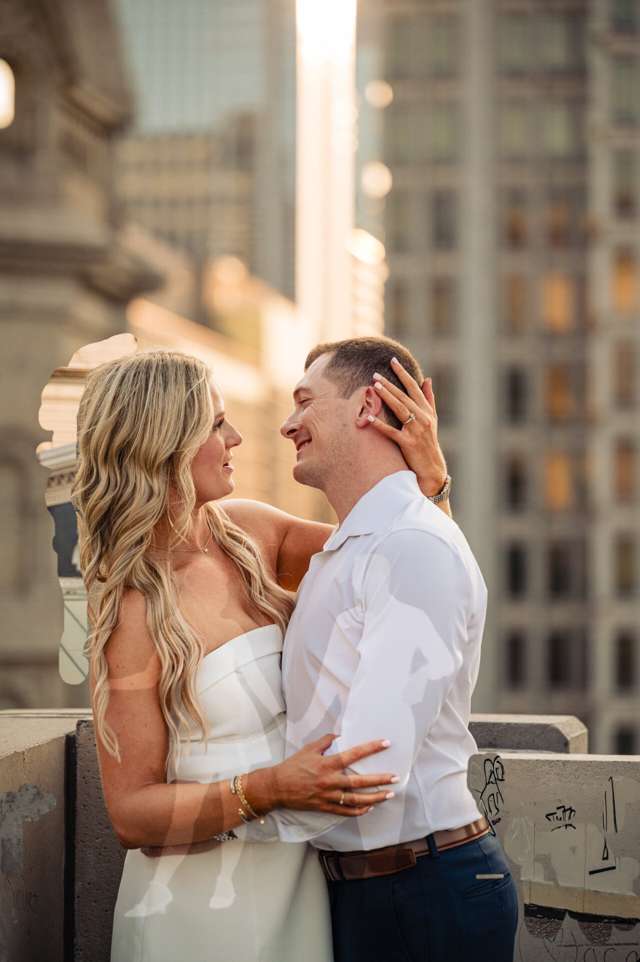Couple embracing affectionately on a Philadelphia rooftop overlooking urban skyline buildings