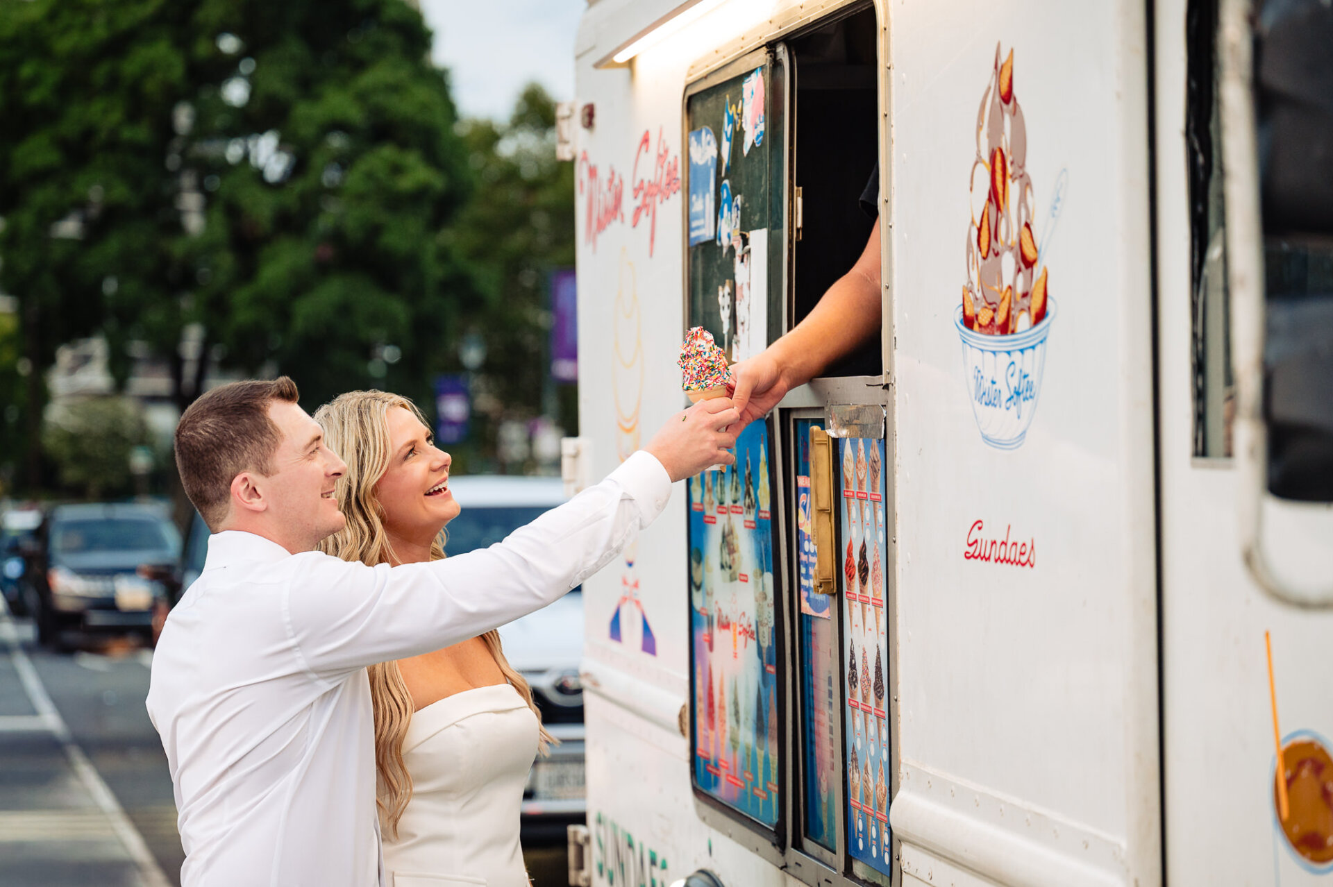 Engaged couple buying soft-serve ice cream cone with rainbow sprinkles from Mister Softee truck in Philadelphia