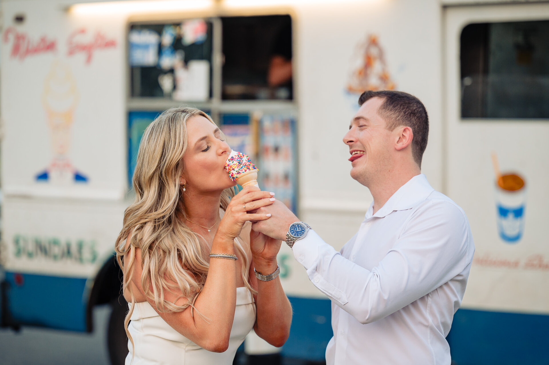 Bride tasting soft-serve ice cream cone held by groom in front of Mister Softee truck