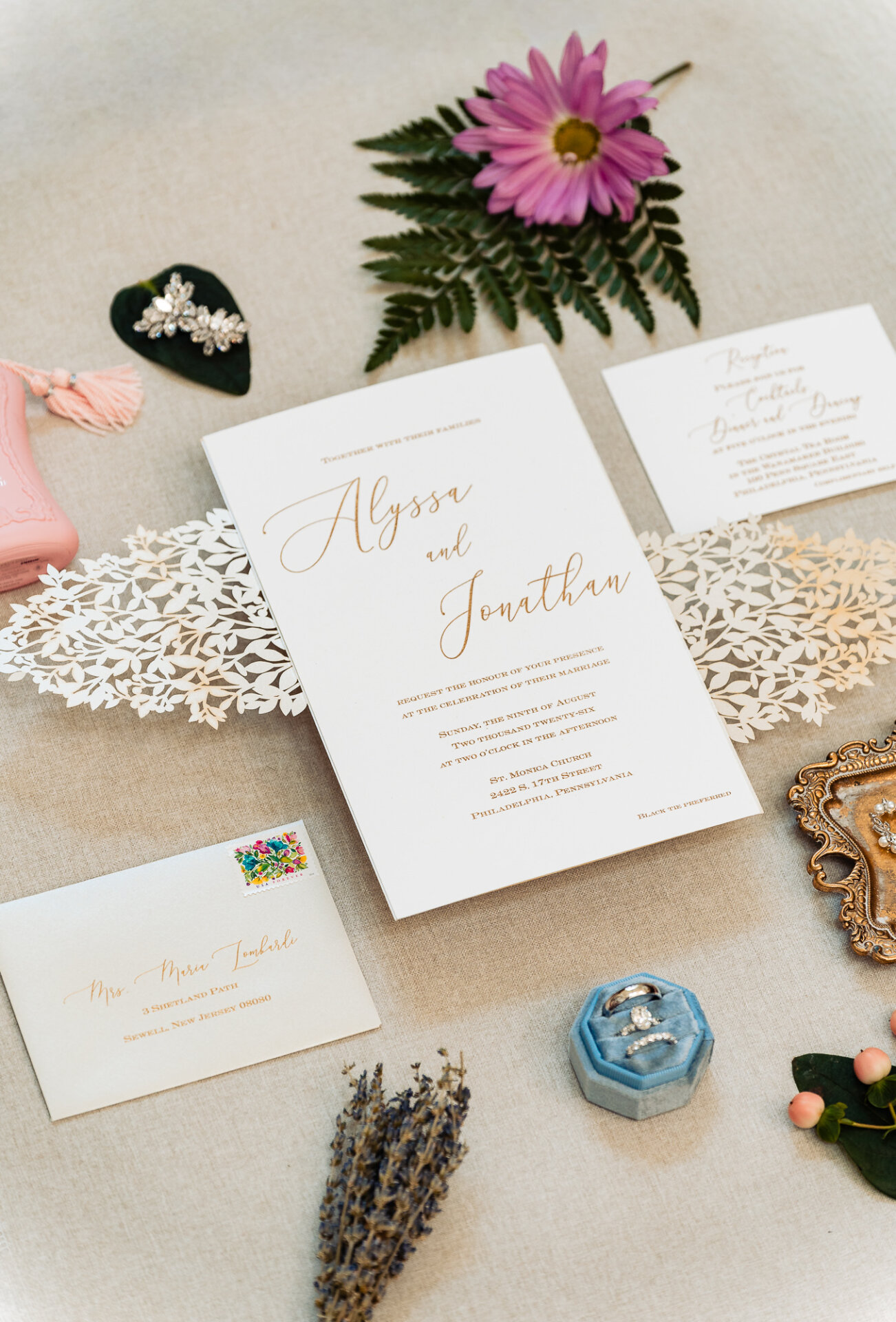 Wedding invitation suite with bridal rings, perfume, jewelry, flowers, and personal details