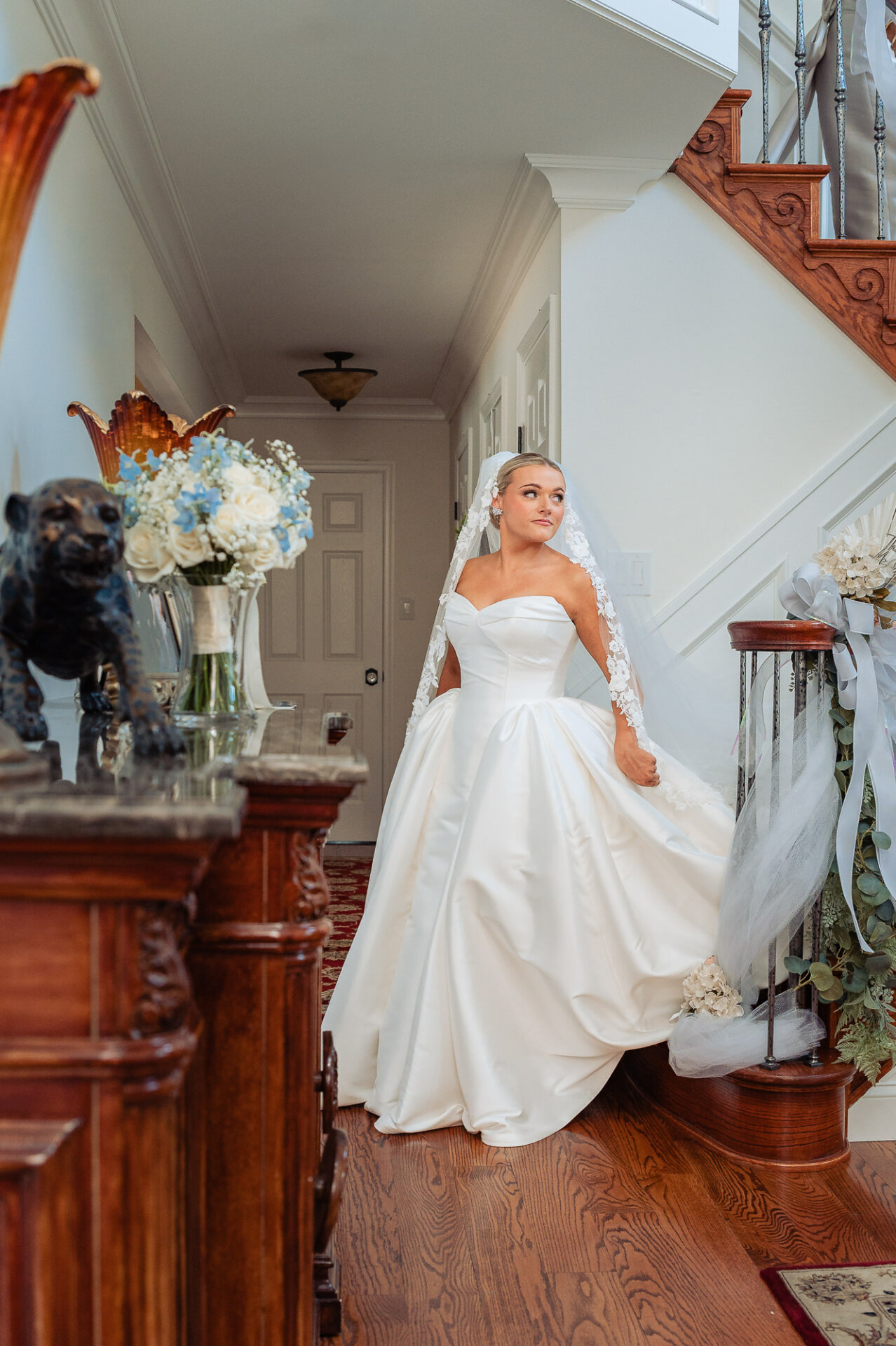 Bride posing on a decorated staircase in her white wedding gown and lace veil