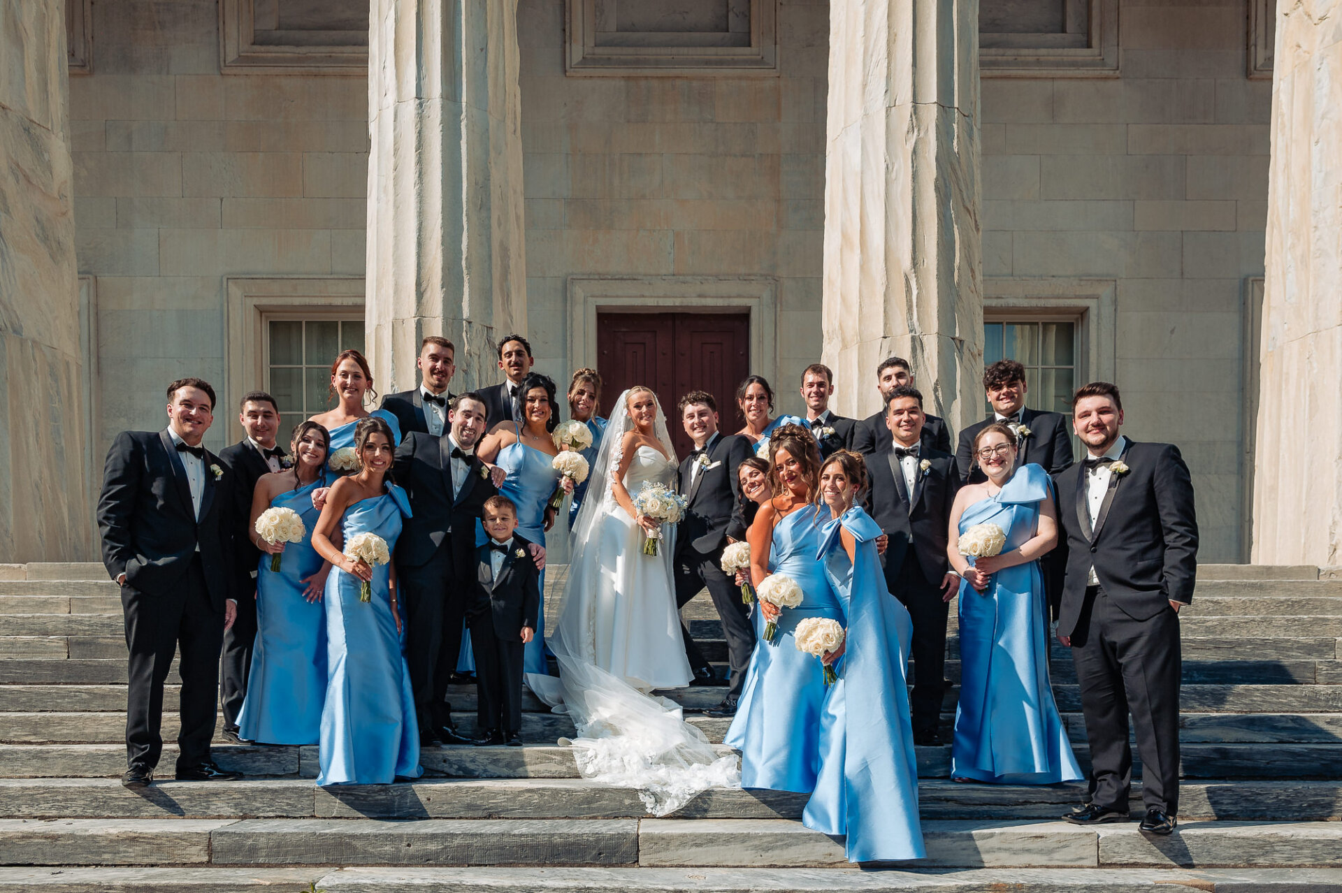 Bride and groom posing with their wedding party on the steps of a historic Philadelphia building