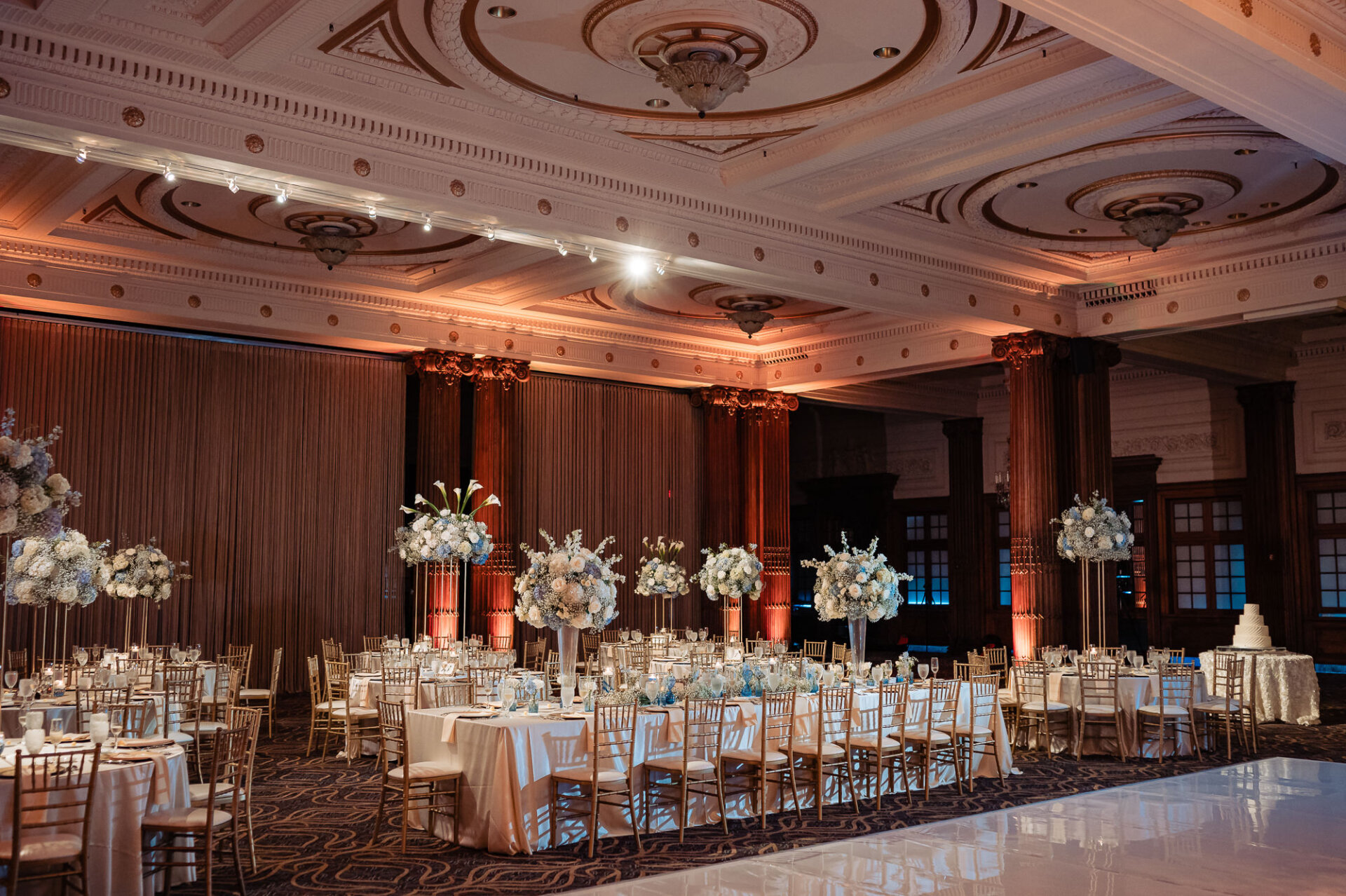 Crystal Tea Room reception tables with tall white and blue floral arrangements and warm uplighting