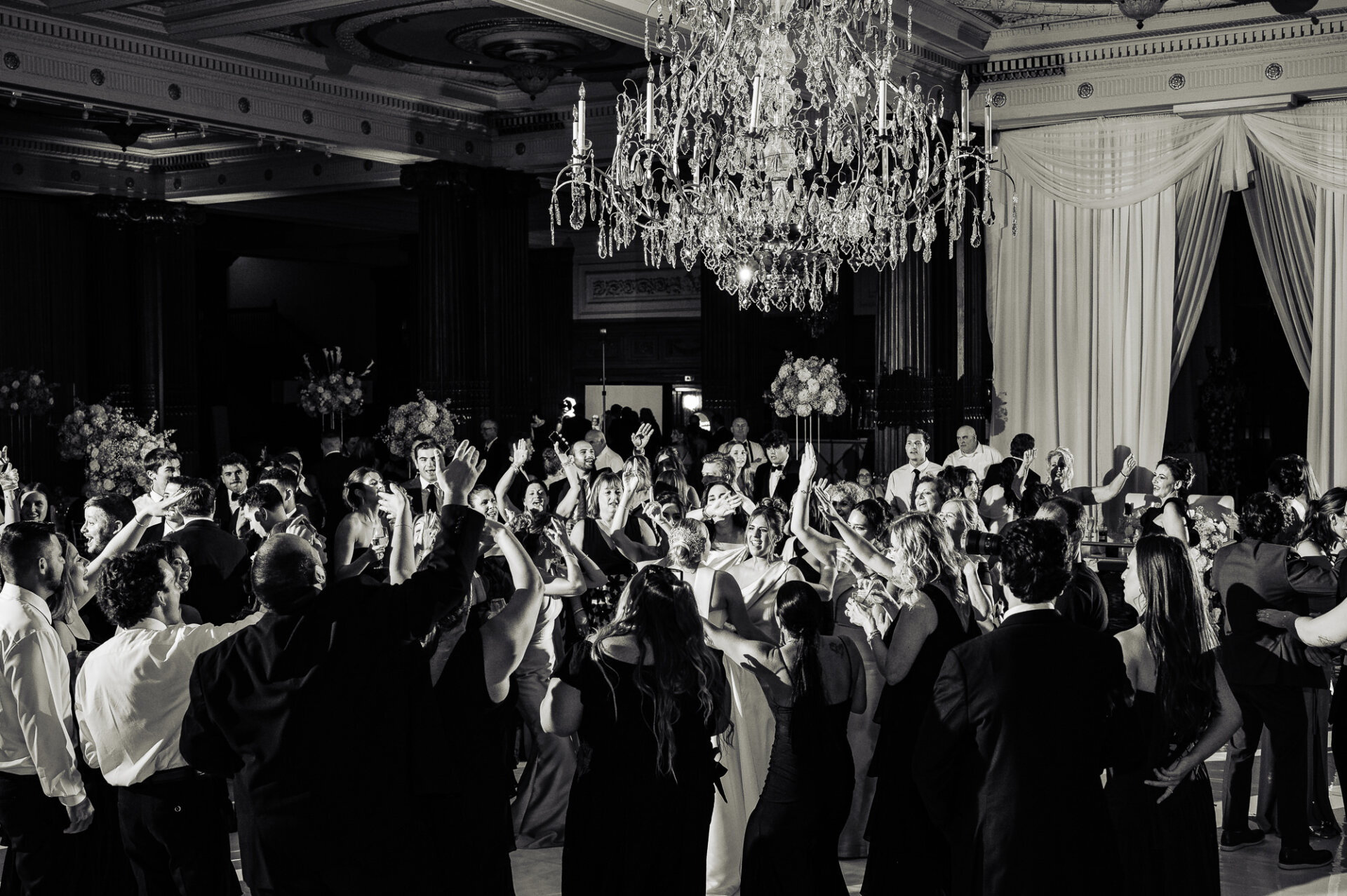 Wedding guests celebrating on the dance floor beneath the Crystal Tea Room chandelier