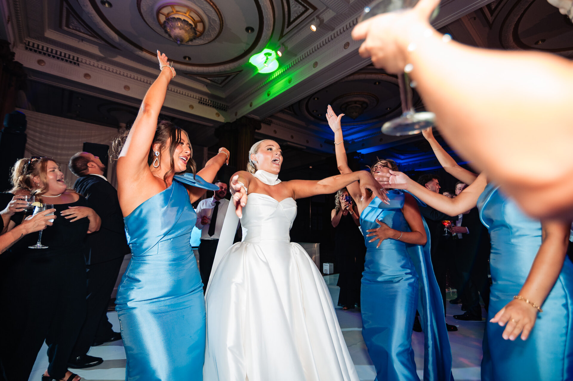 Bride dancing with bridesmaids in blue dresses during a lively Crystal Tea Room wedding reception