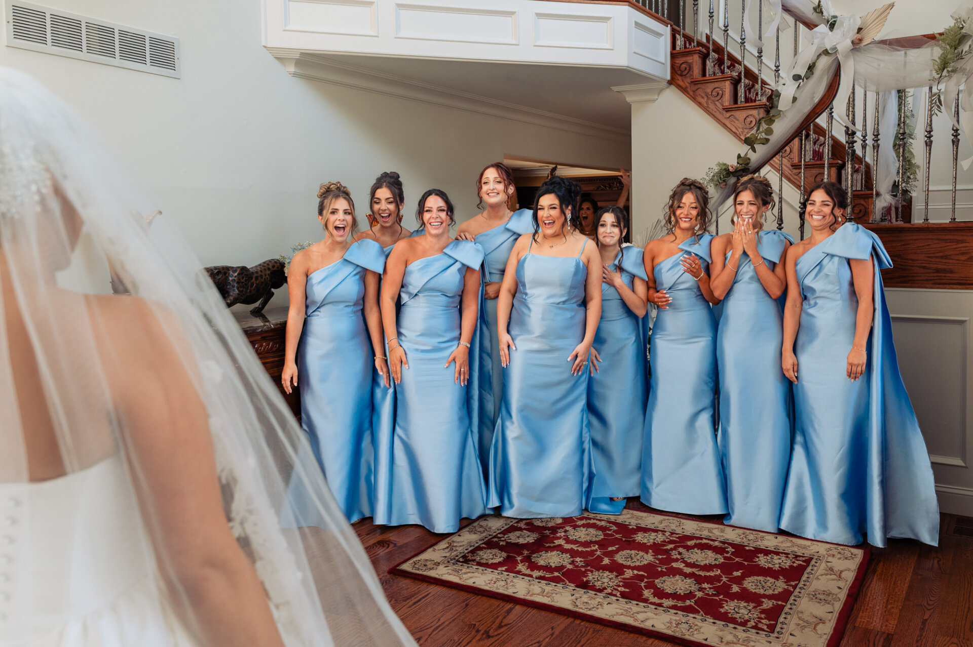 Bridesmaids reacting with excitement during their first look at the bride in her wedding gown