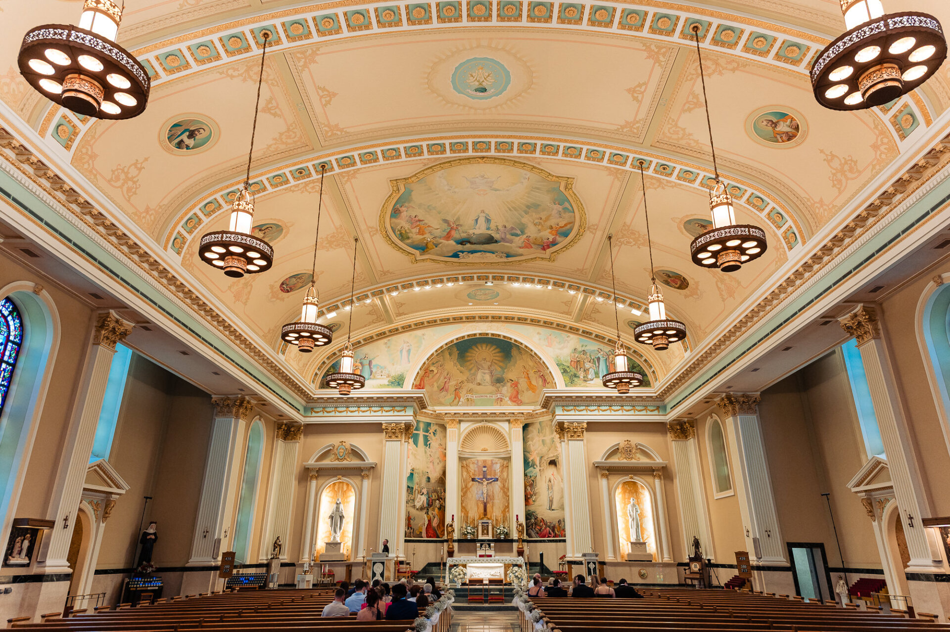 Grand church interior featuring an ornate painted ceiling and floral wedding ceremony decorations