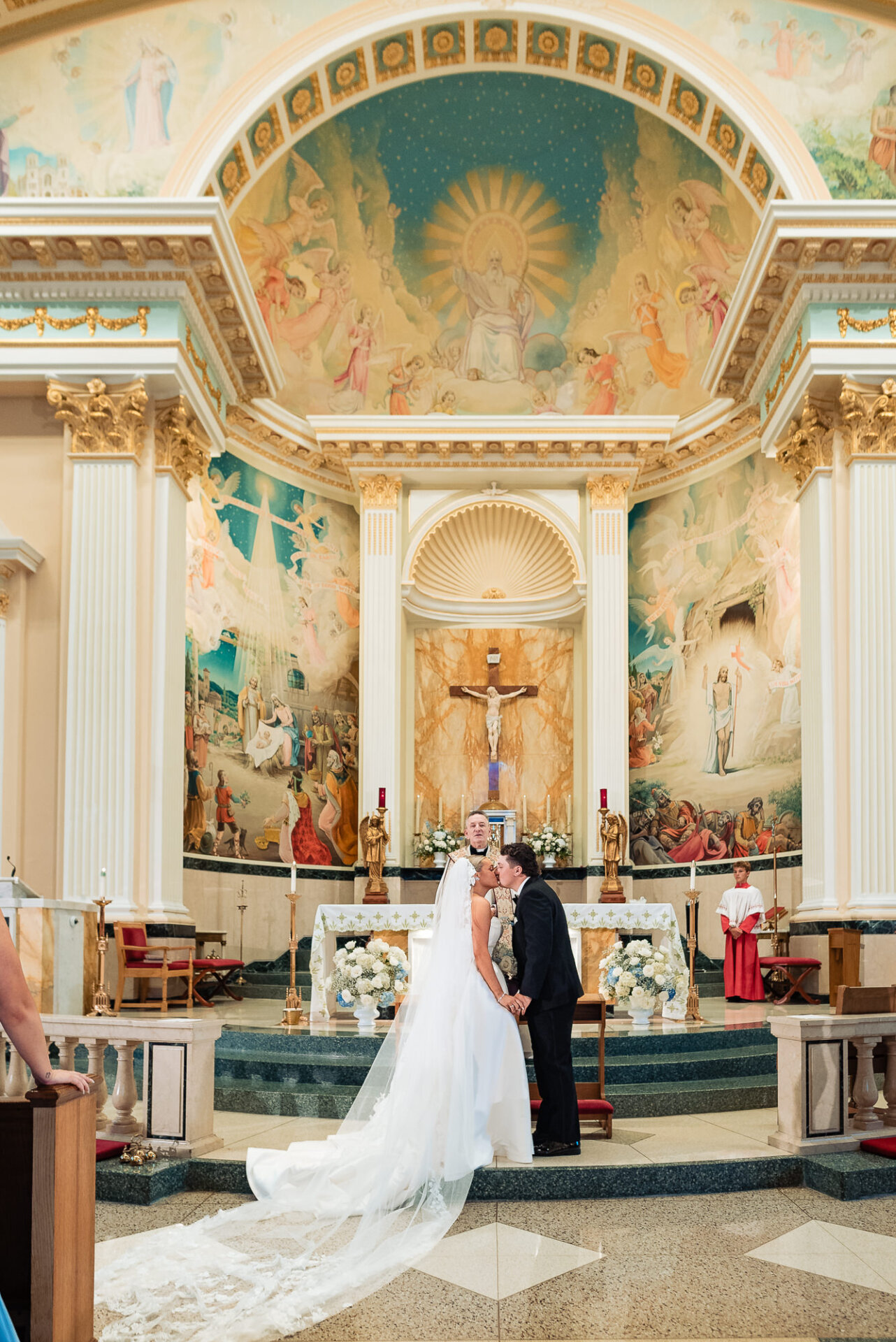 Bride and groom sharing their first kiss at the altar during their Catholic wedding ceremony