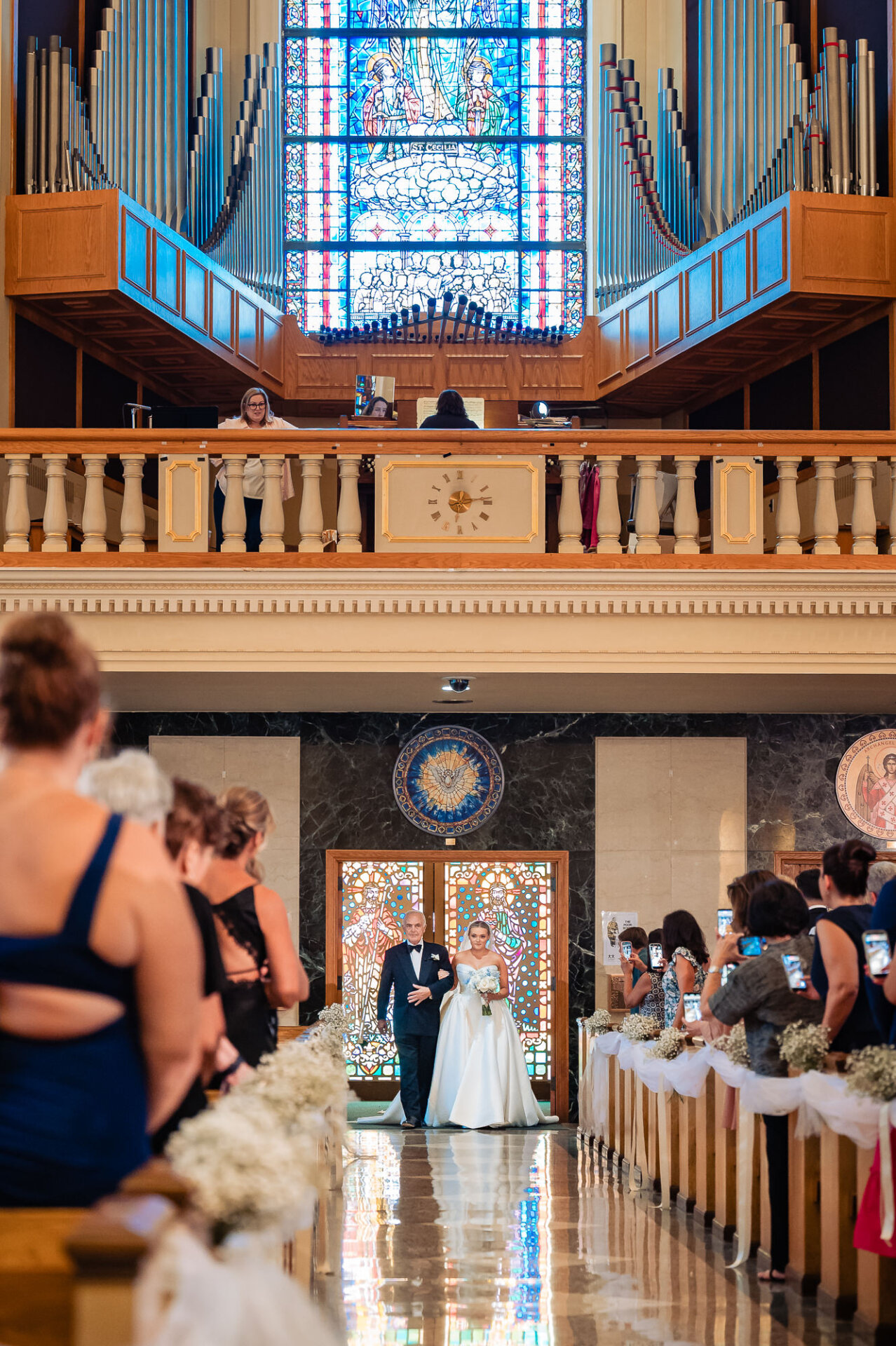 Bride walking down the church aisle with her escort as wedding guests watch