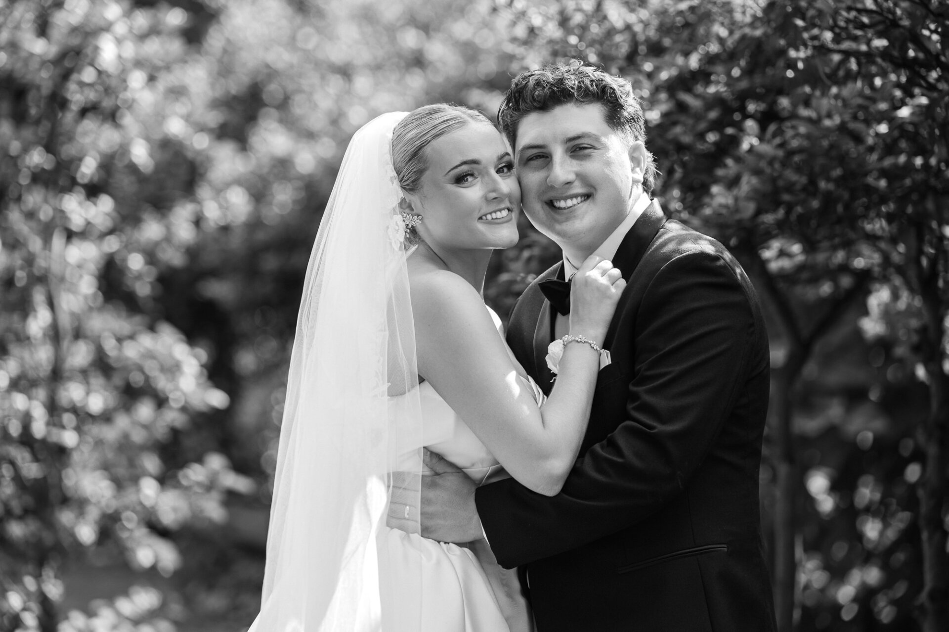 Black-and-white wedding portrait of the bride and groom smiling together outdoors