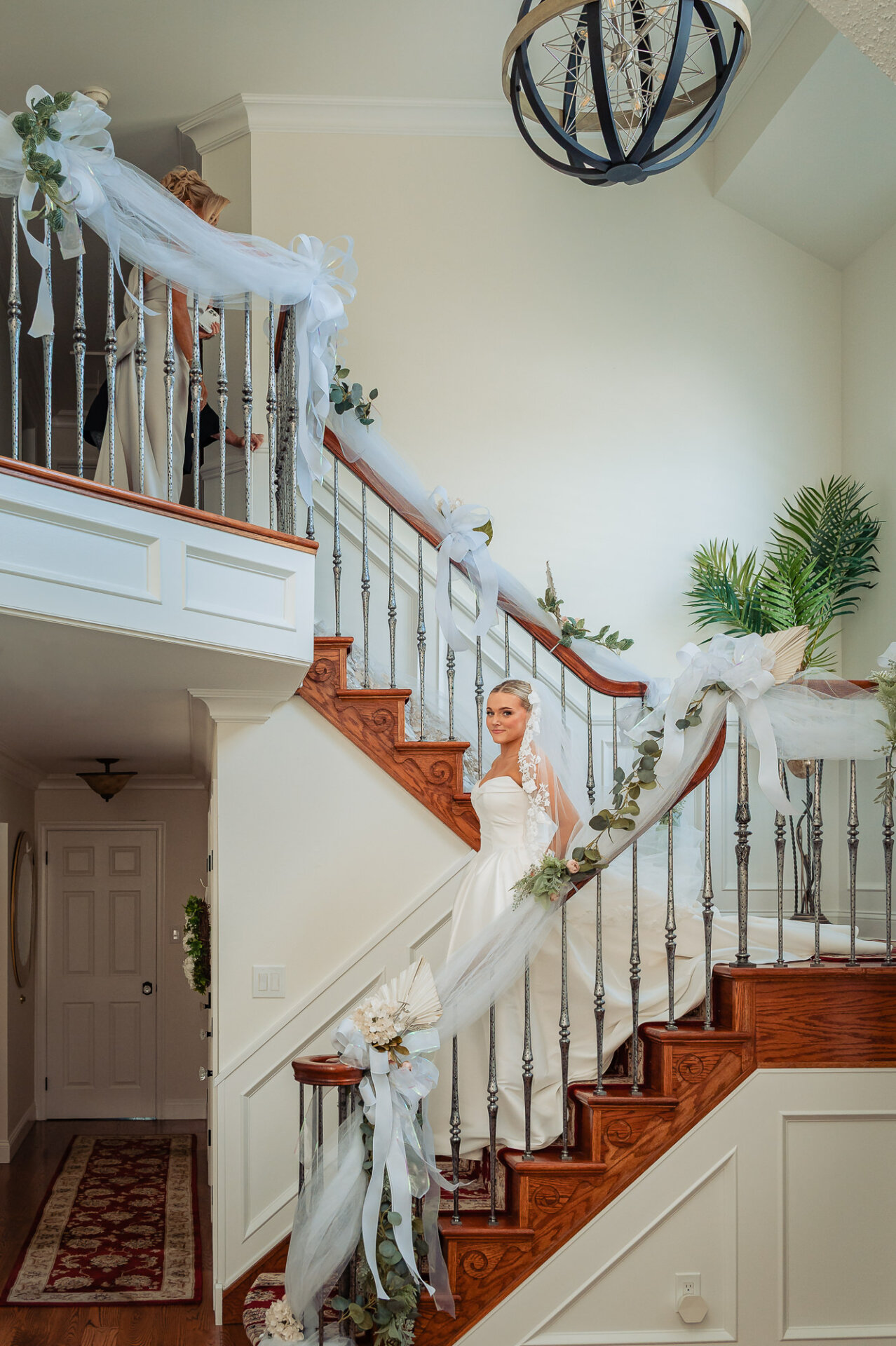 Bride posing on a decorated staircase in her white wedding gown and lace veil