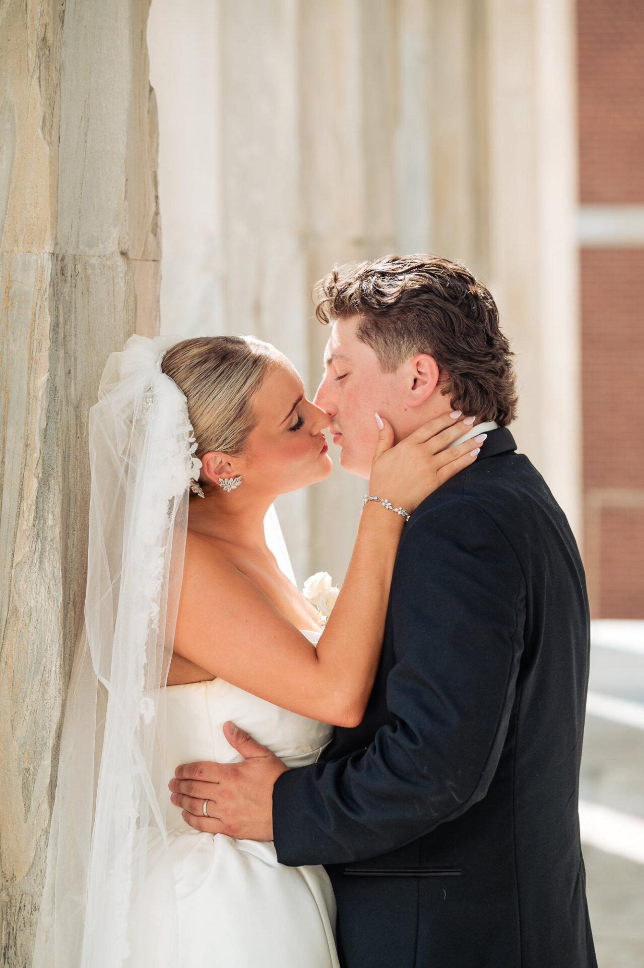 Bride and groom sharing an intimate moment beside the stone columns after their ceremony