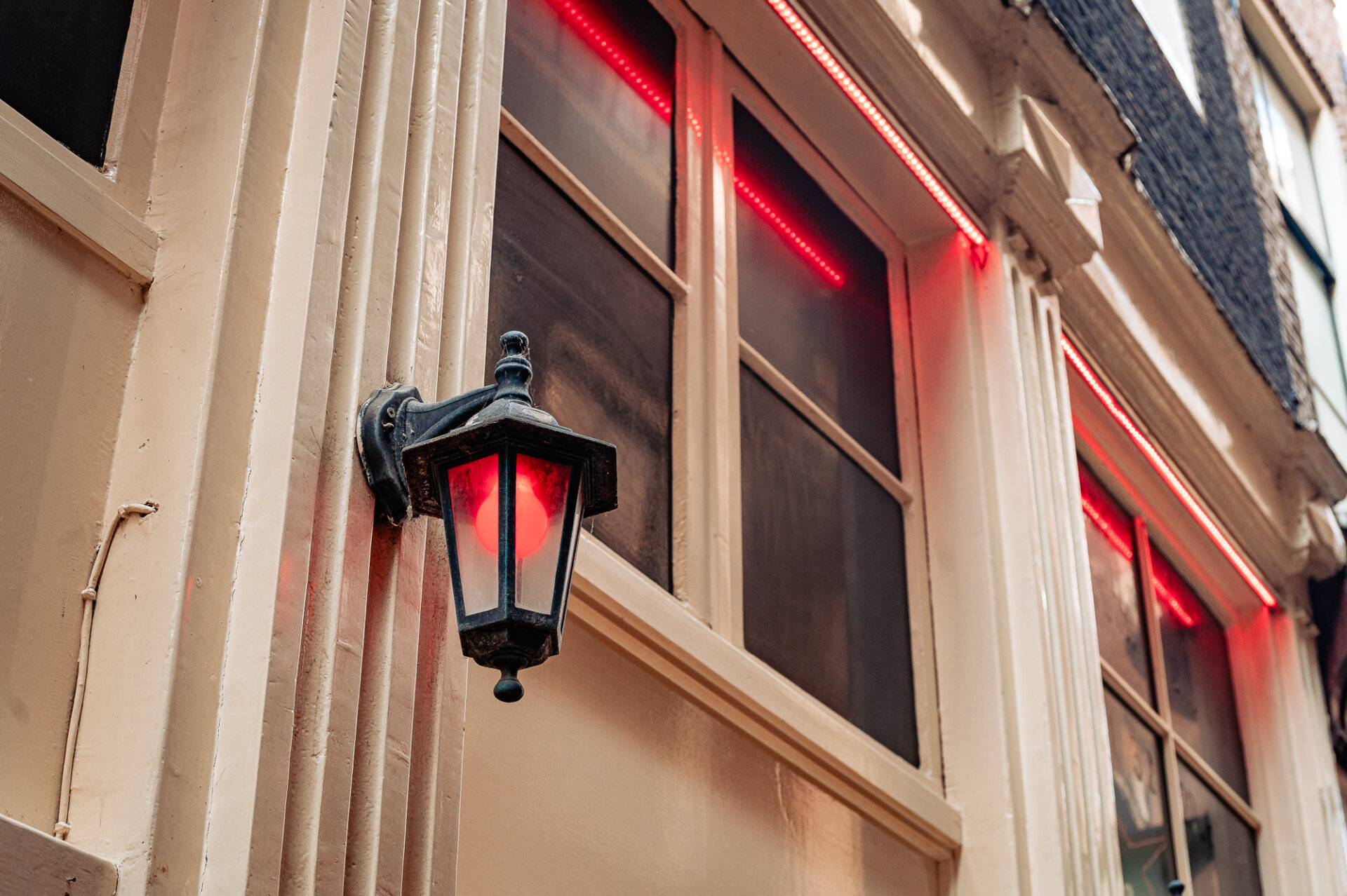 Traditional red lantern glowing beside illuminated windows in Amsterdam’s Red Light District