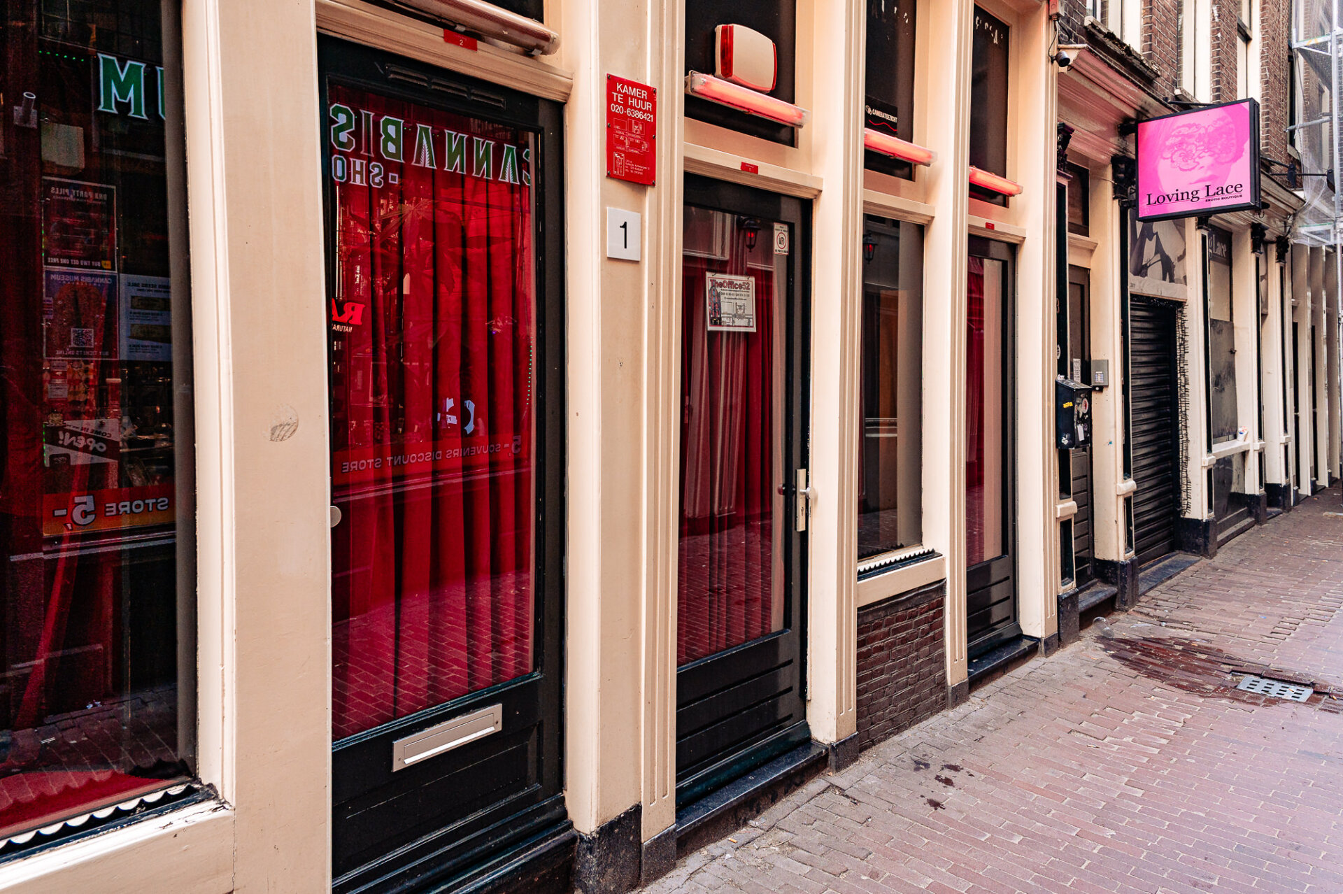 305. Red-curtained windows lining a narrow street in Amsterdam’s Red Light District