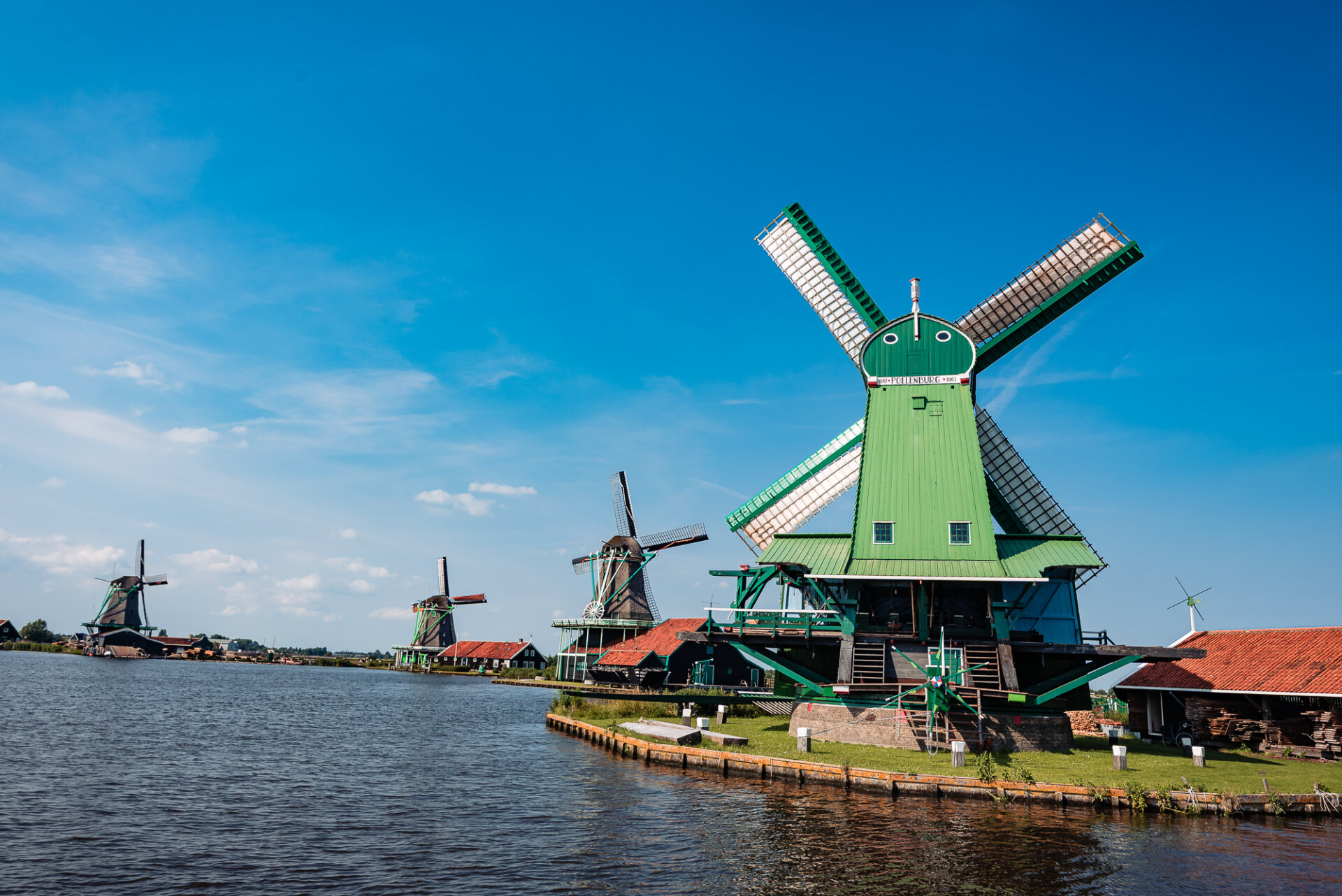 Historic green windmills lining the waterfront at Zaanse Schans in the Netherlands