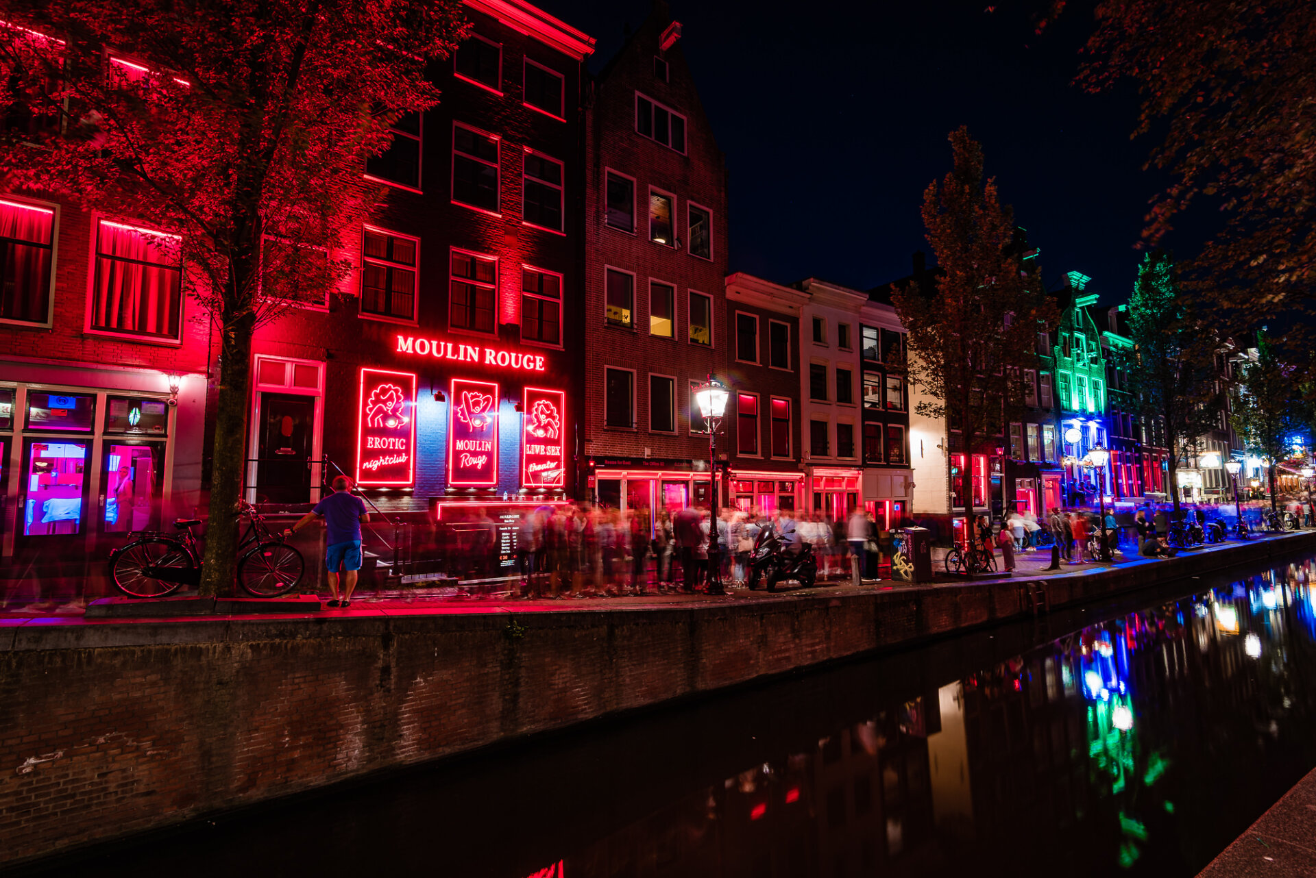 Amsterdam Red Light District glowing with neon lights along a canal at night