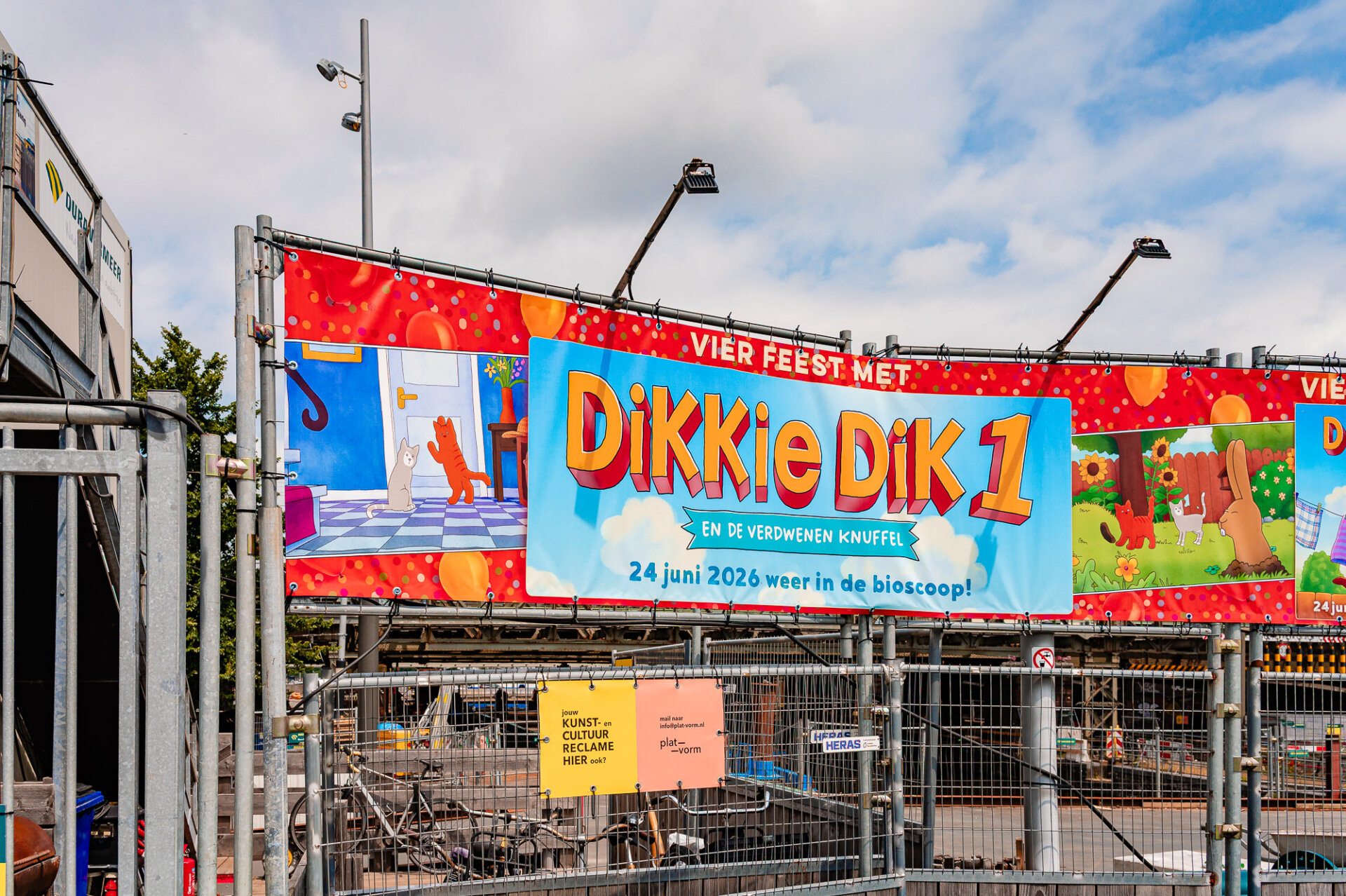 Colourful Dikkie Dik advertisement displayed at an outdoor construction site in Amsterdam