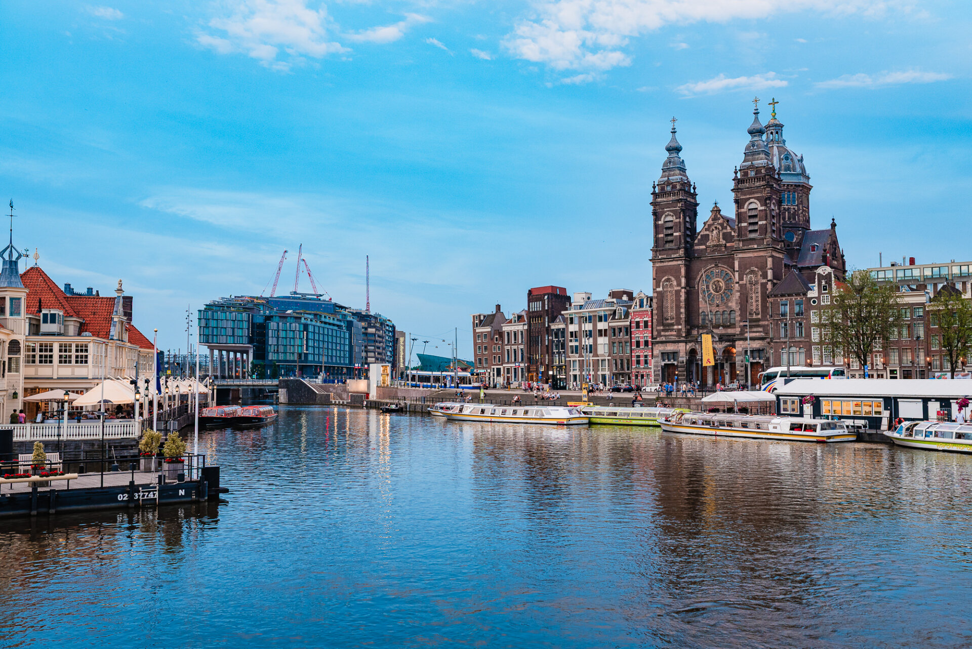 Amsterdam waterfront view featuring the Basilica of Saint Nicholas and boats along the harbour