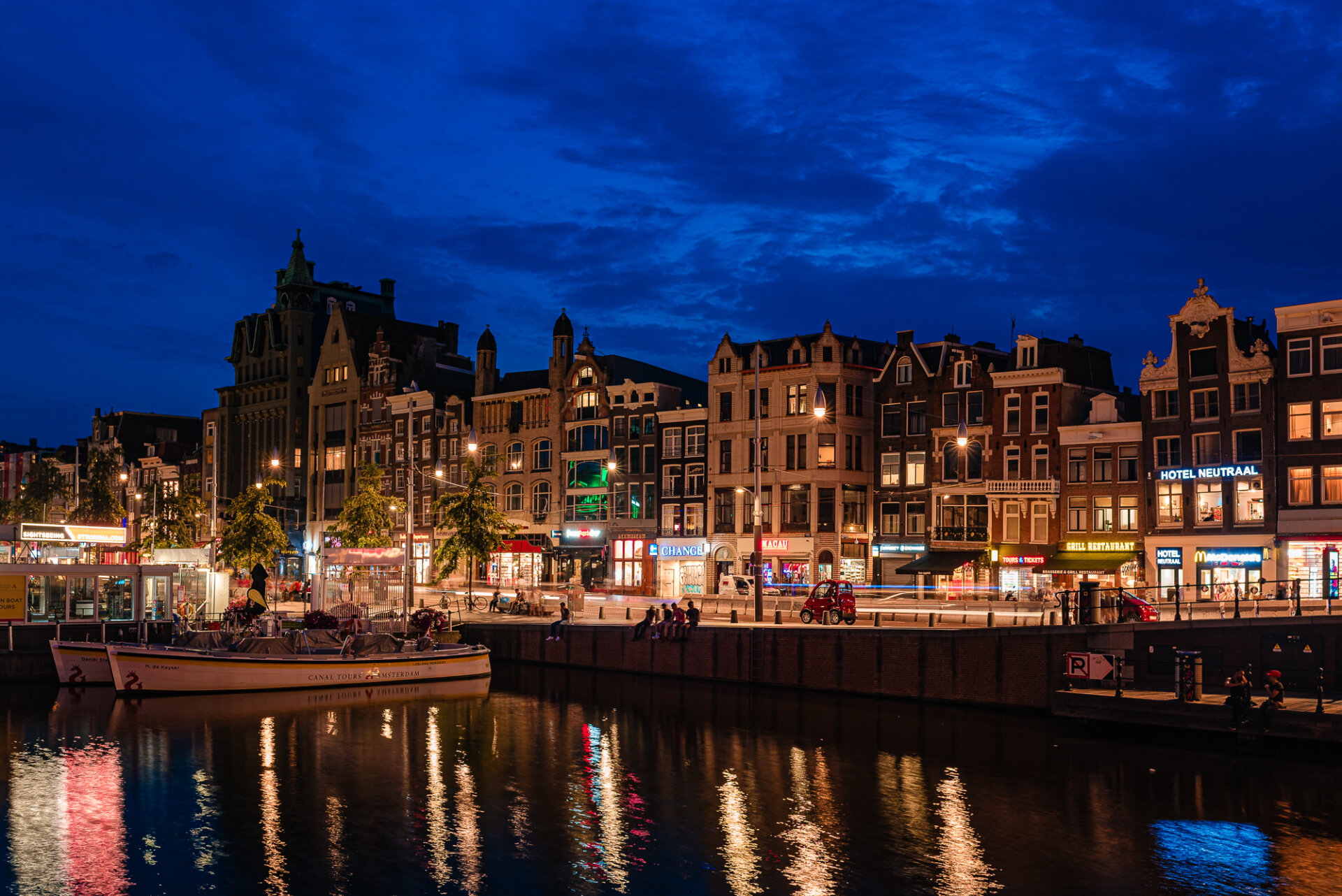 Amsterdam canal at blue hour with illuminated historic buildings and colourful reflections on the water