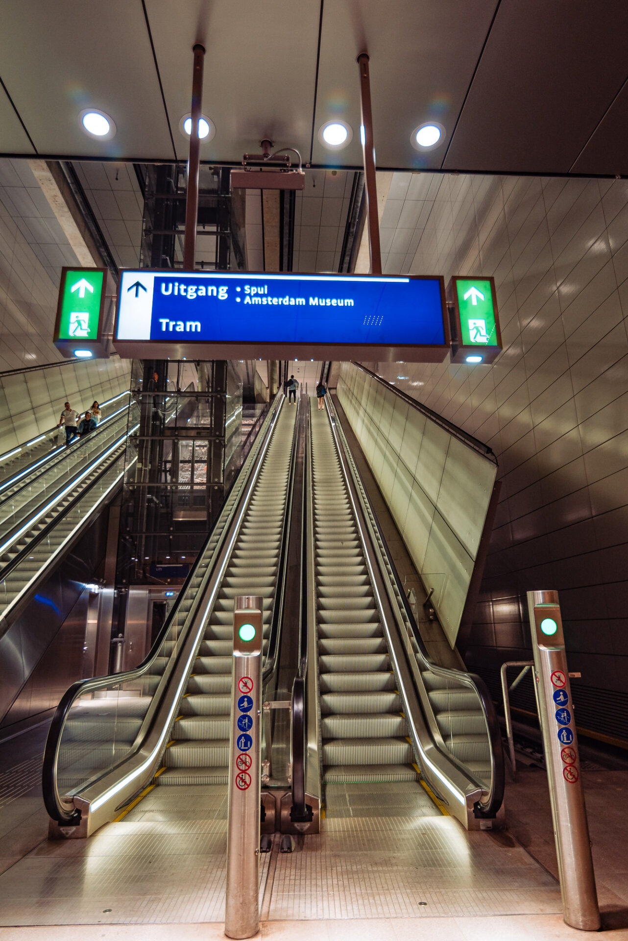 Escalators inside an Amsterdam metro station leading toward the Spui and Amsterdam Museum exit