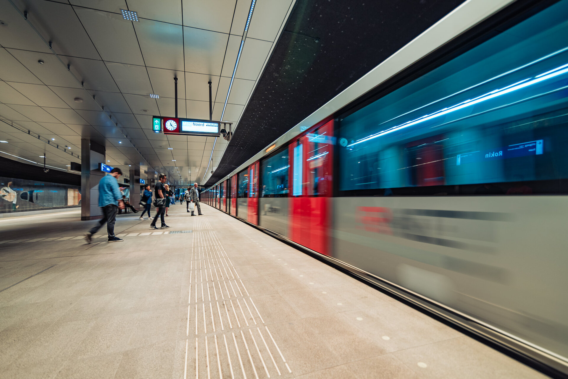 Amsterdam metro train arriving at the platform as passengers wait beside the tracks