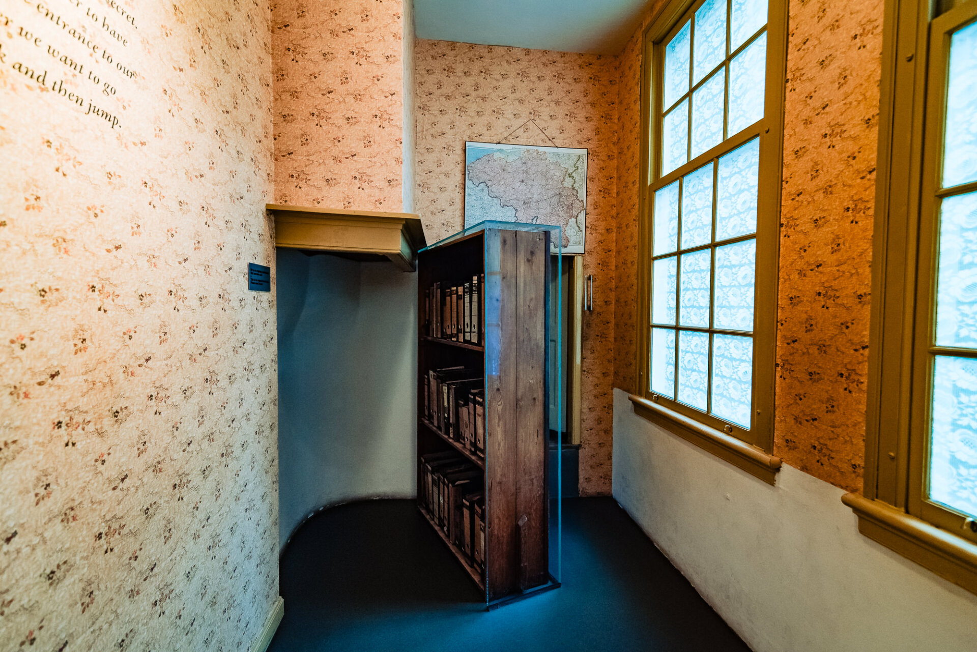 Recreated historic room with bookshelves, patterned walls and tall windows at the Anne Frank House