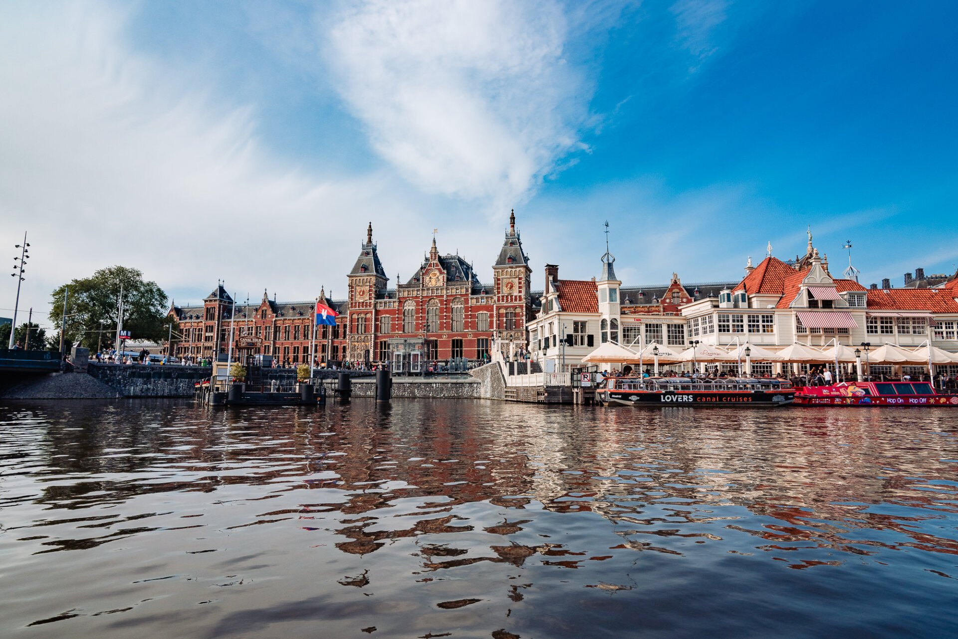 Amsterdam Centraal Station viewed across the waterfront with canal cruise boats in the foreground