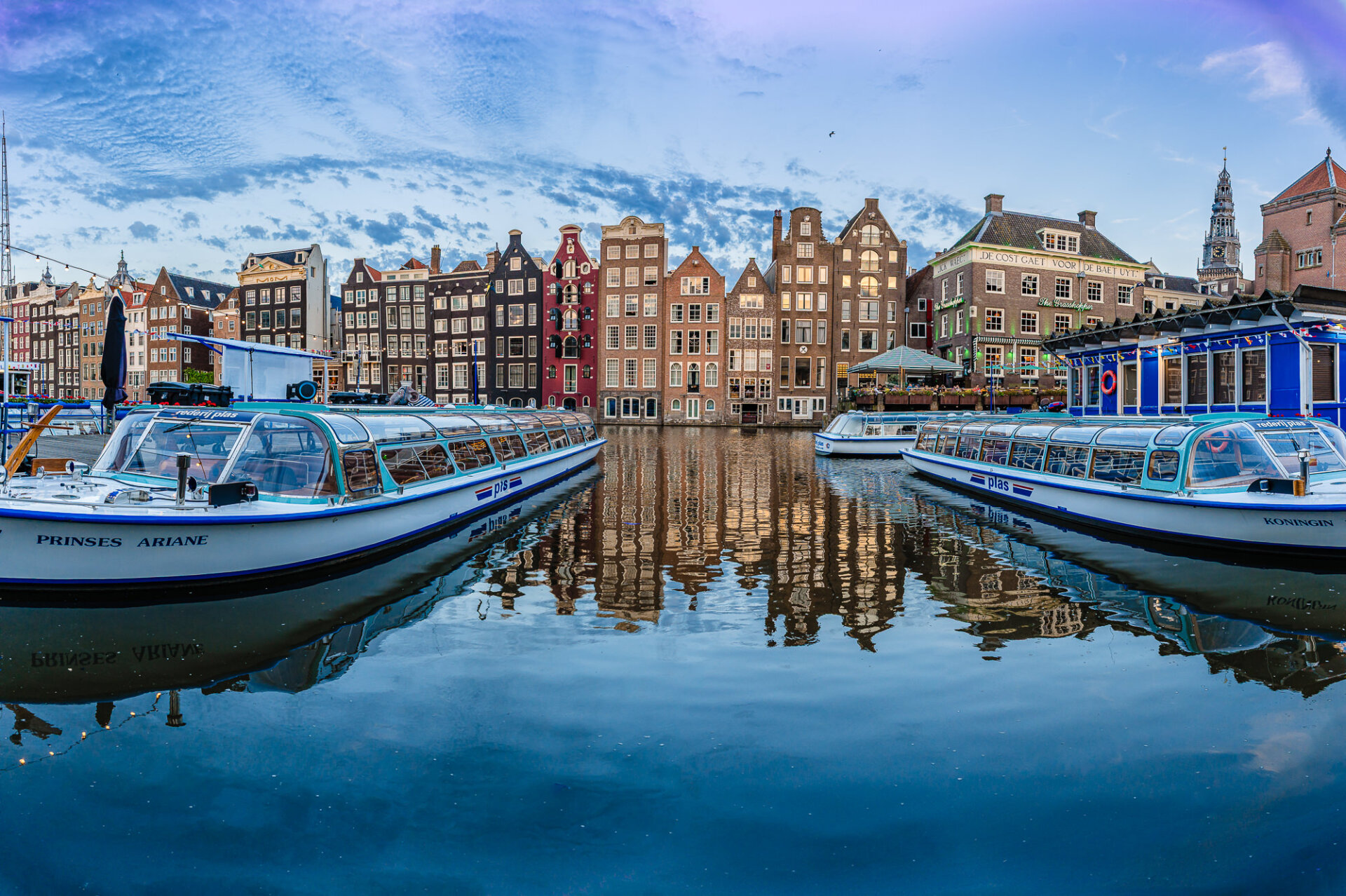 Amsterdam canal boats framed by historic narrow houses and reflections in calm water