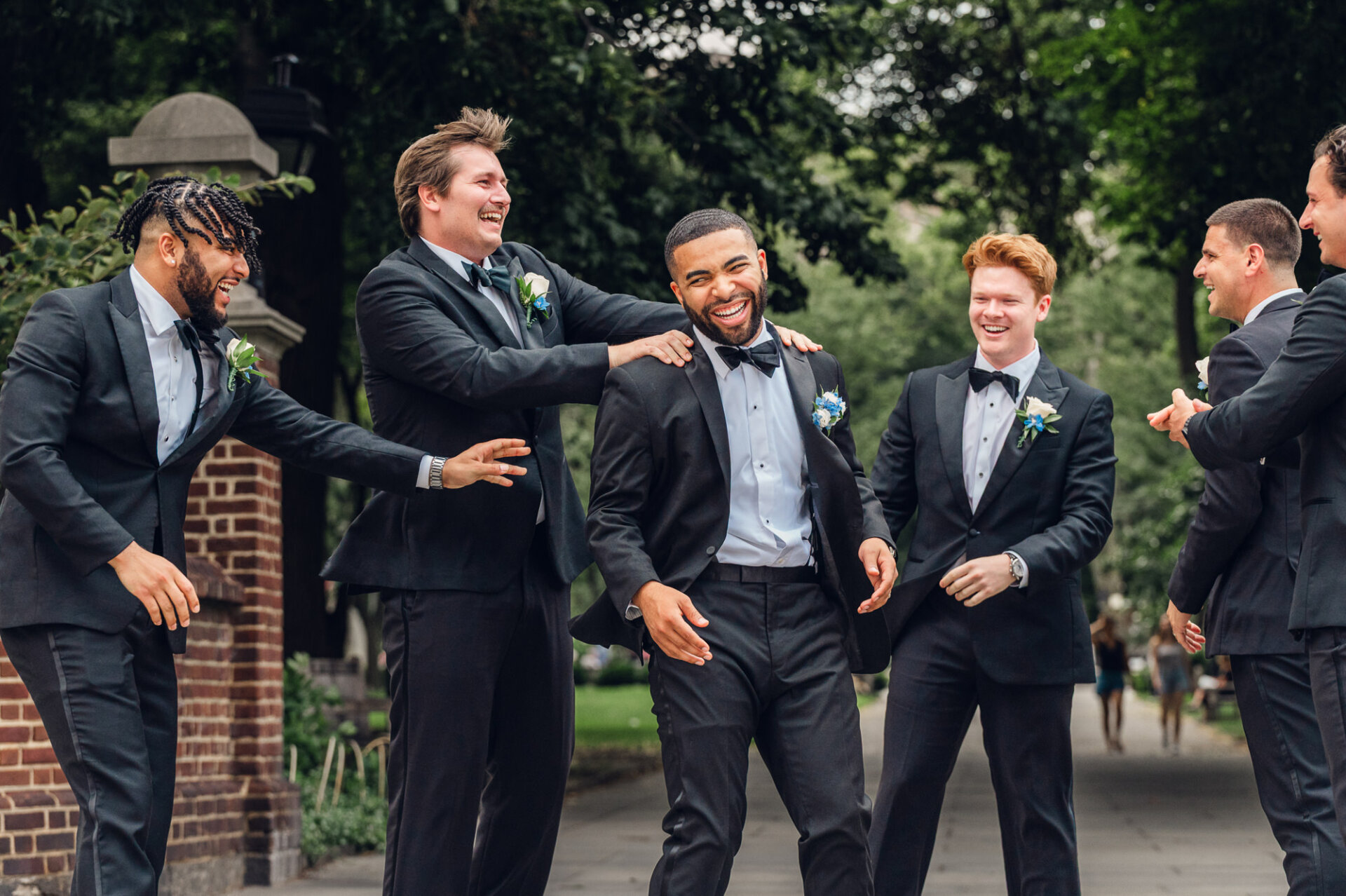 Groom laughs with his groomsmen during outdoor wedding portraits in Philadelphia.