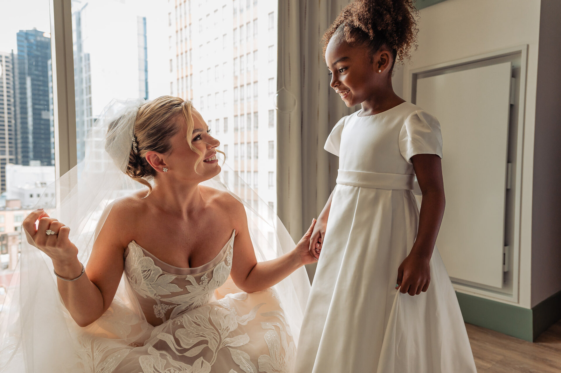 Bride shares a joyful moment with a flower girl before the wedding ceremony.