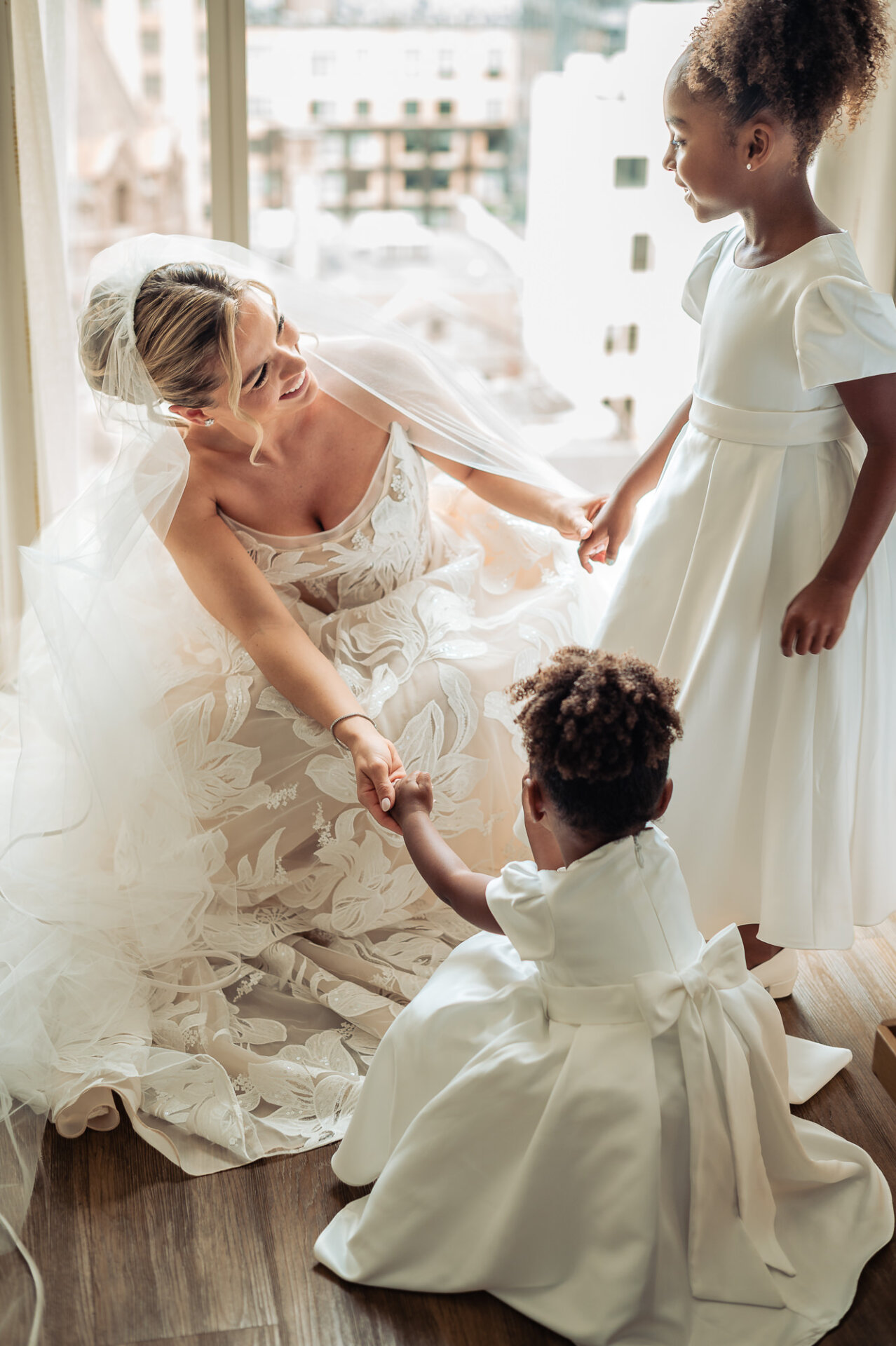 Bride holds hands with two flower girls while getting ready for her wedding at The Ben Philadelphia.