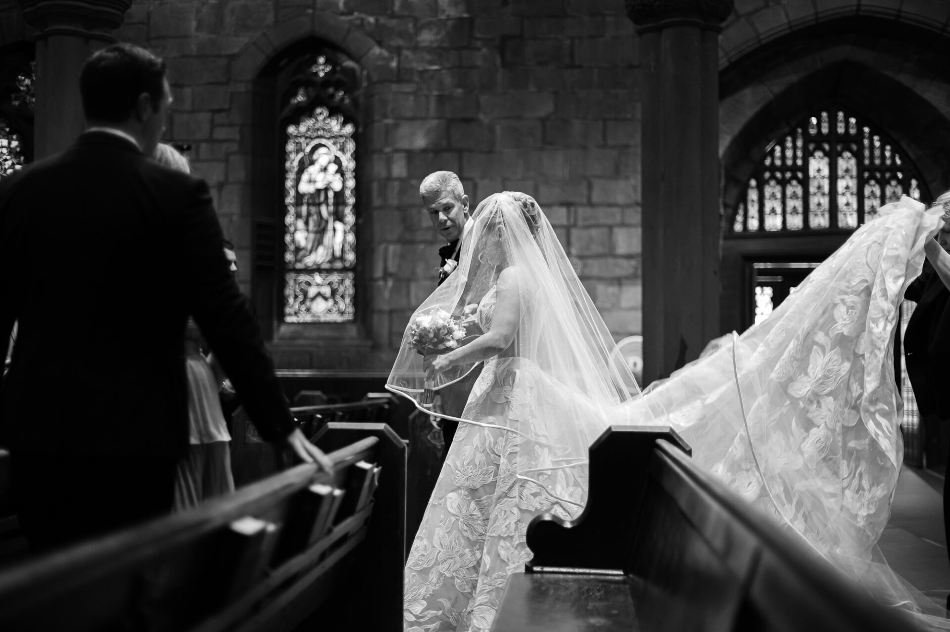 Bride walking through the church with her father as her floral train flows behind her.