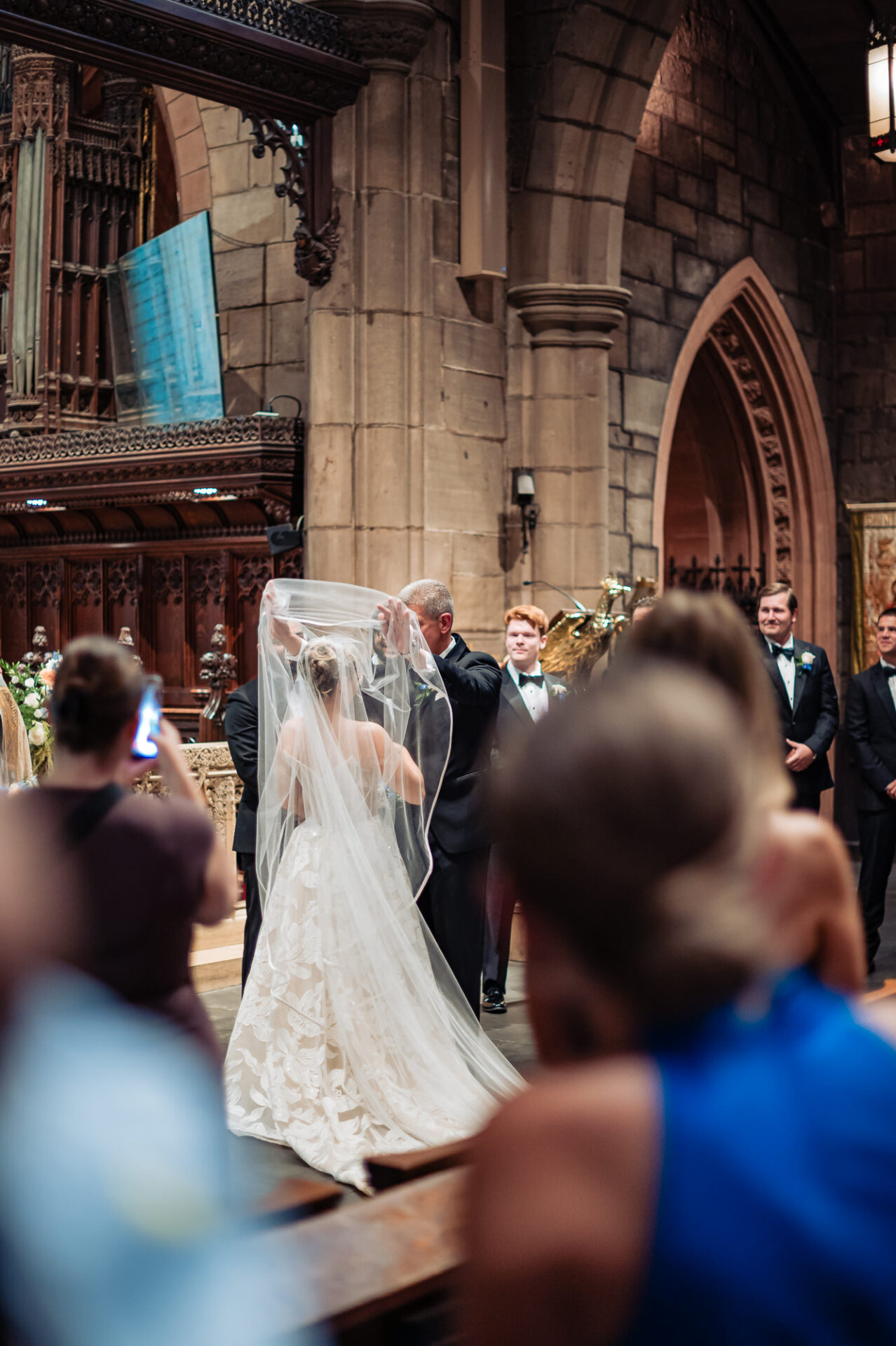 Bride’s father lifts her veil before presenting her to the groom at the church altar.