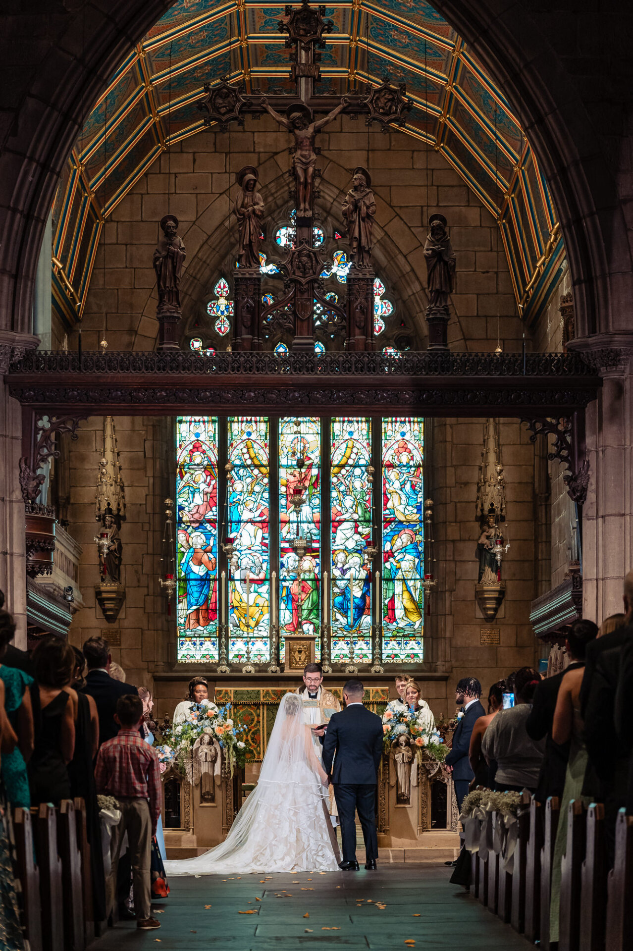 Bride and groom standing beneath stained-glass windows during their church wedding ceremony.