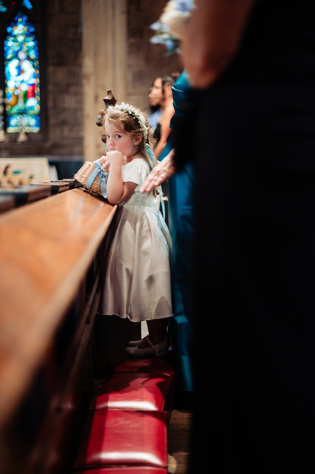 Flower girl in a white dress stands inside the church during an elegant Philadelphia wedding.
