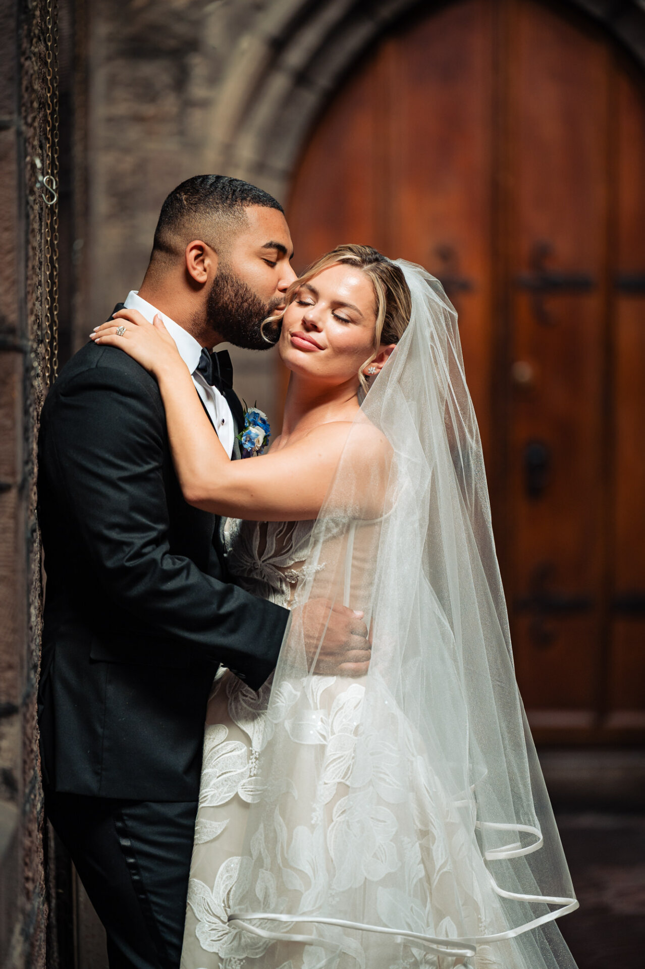 Groom kisses the bride’s cheek outside Saint Mark’s Church during their Philadelphia wedding.