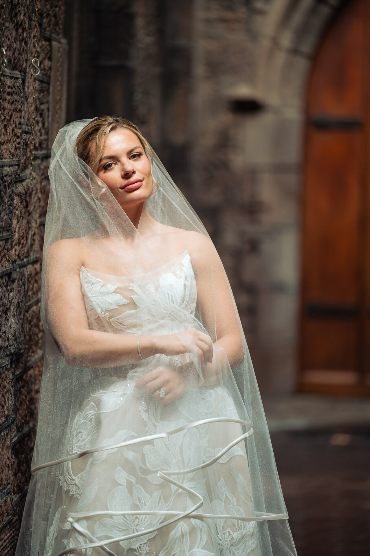 Bride poses beneath her veil at Saint Mark’s Church before her wedding at The Ben Philadelphia.