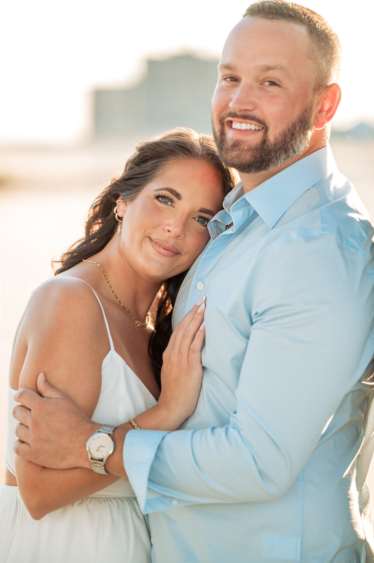 Close-up engagement portrait of a couple embracing in warm golden-hour light at Margate Beach