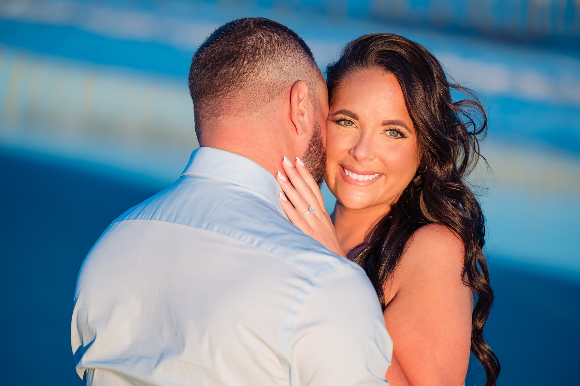 Woman smiling at the camera while embracing her partner during their Margate Beach engagement session