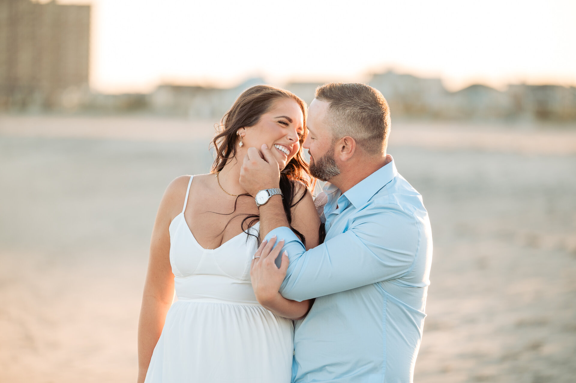 Man gently touching his smiling partner's face during a romantic engagement portrait on Margate Beach