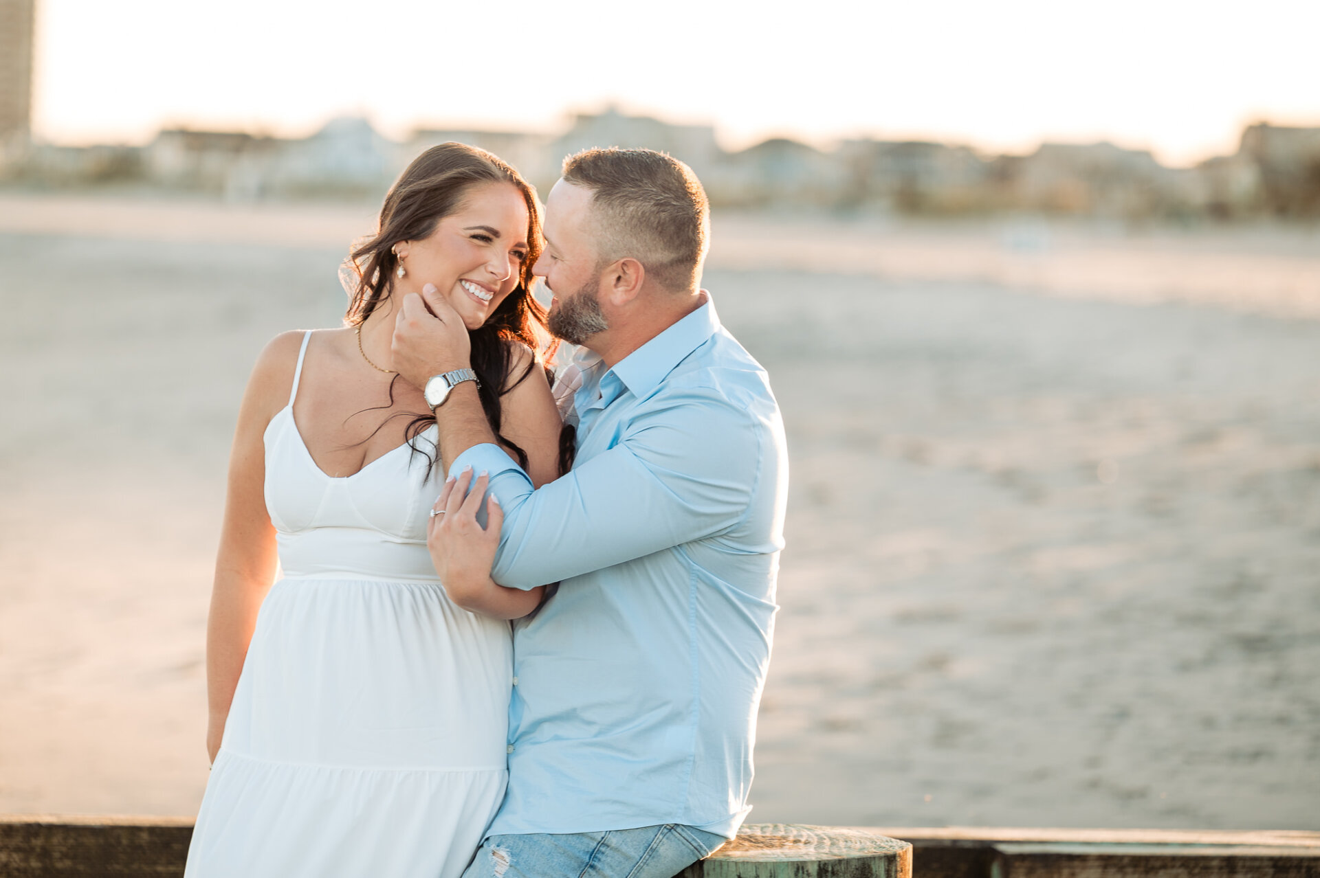Man gently touching his smiling partner's face during a romantic engagement portrait on Margate Beach