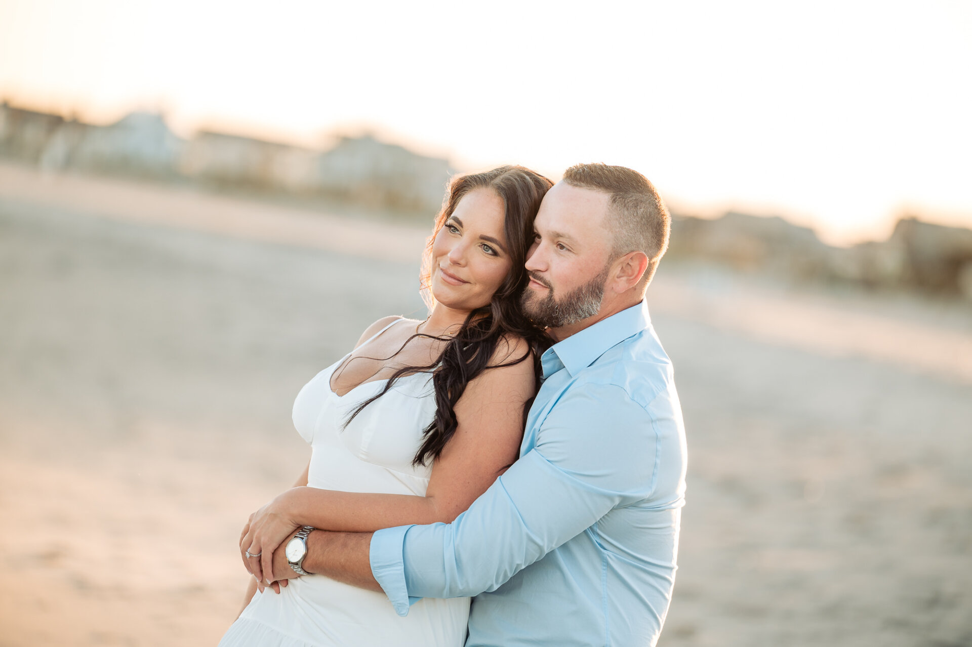 Smiling couple embracing on the beach during their sunset engagement session in Margate, New Jersey