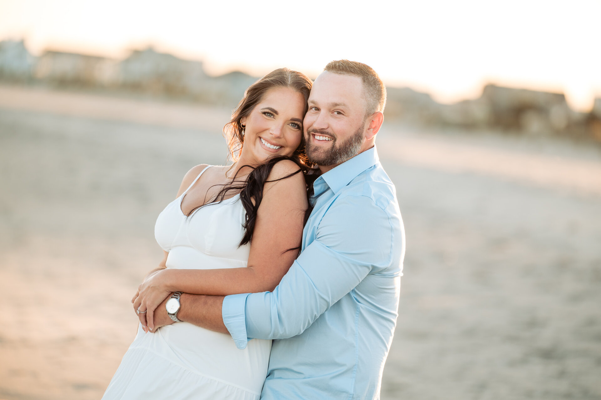 Smiling couple embracing on the beach during their sunset engagement session in Margate, New Jersey