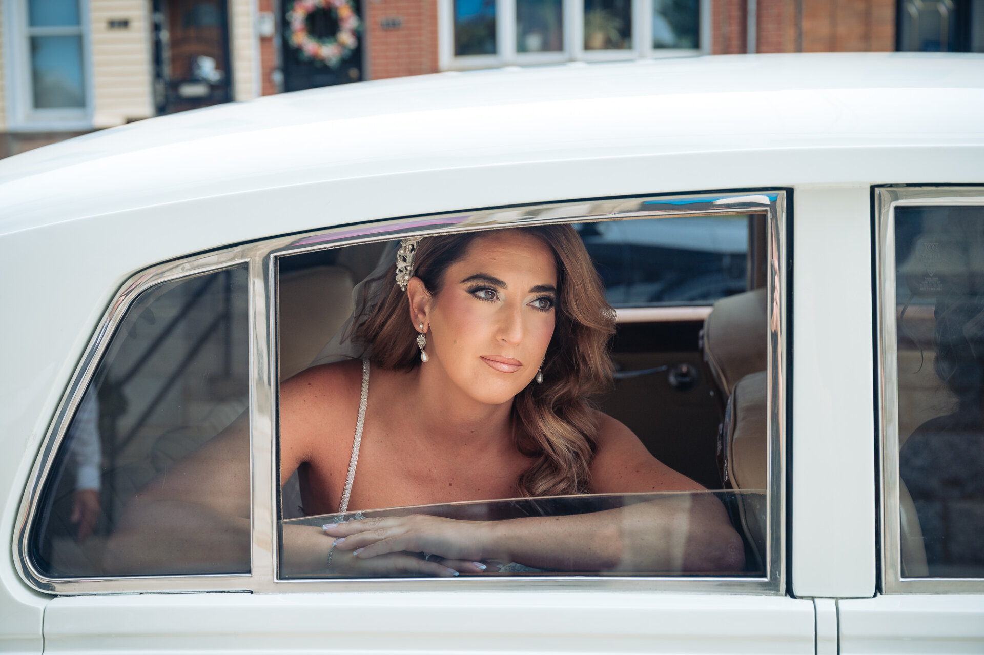 Portrait of bride looking through window of classic white wedding car