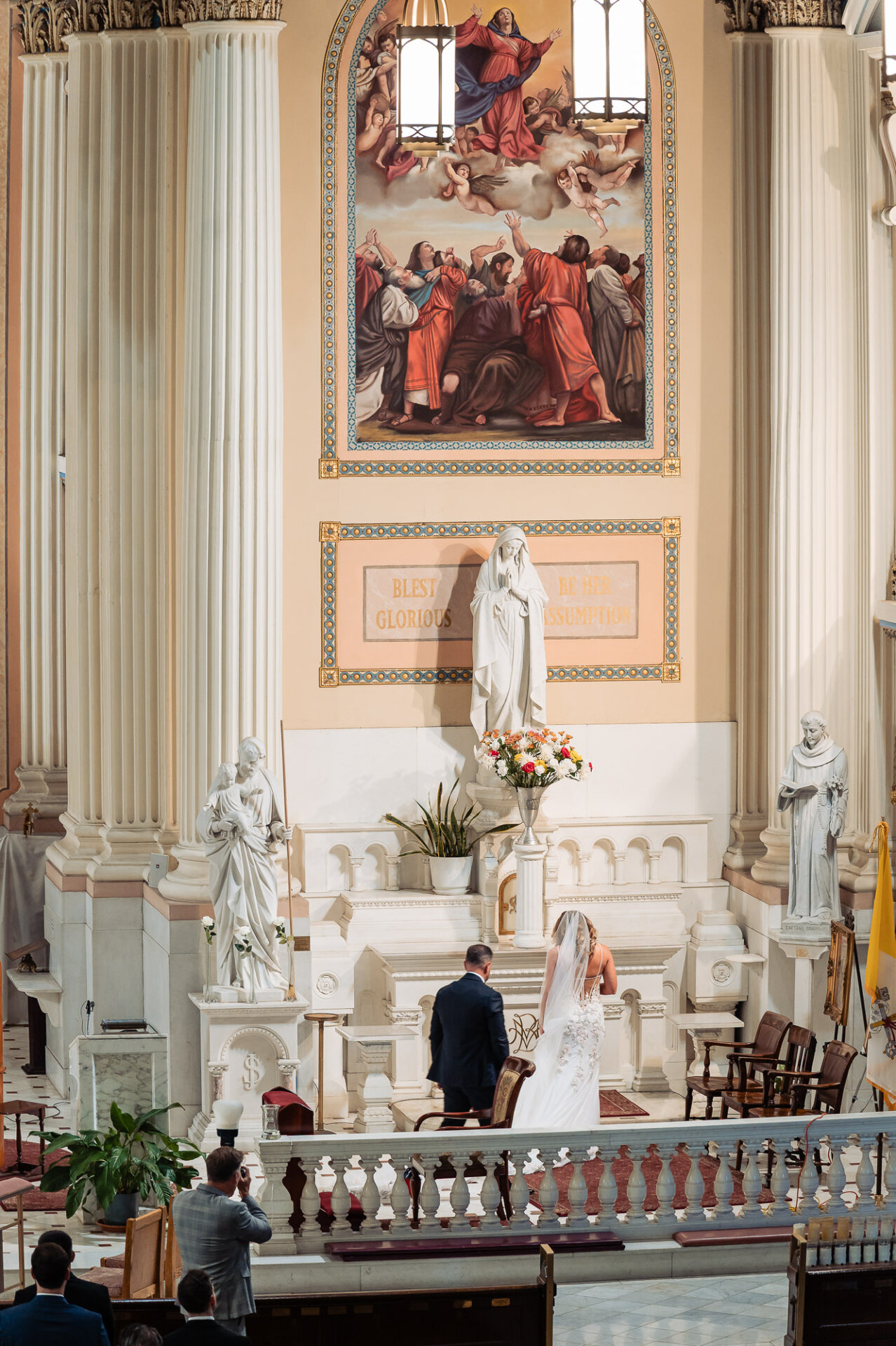 High angle view of bride and groom kneeling at altar inside ornate Catholic church